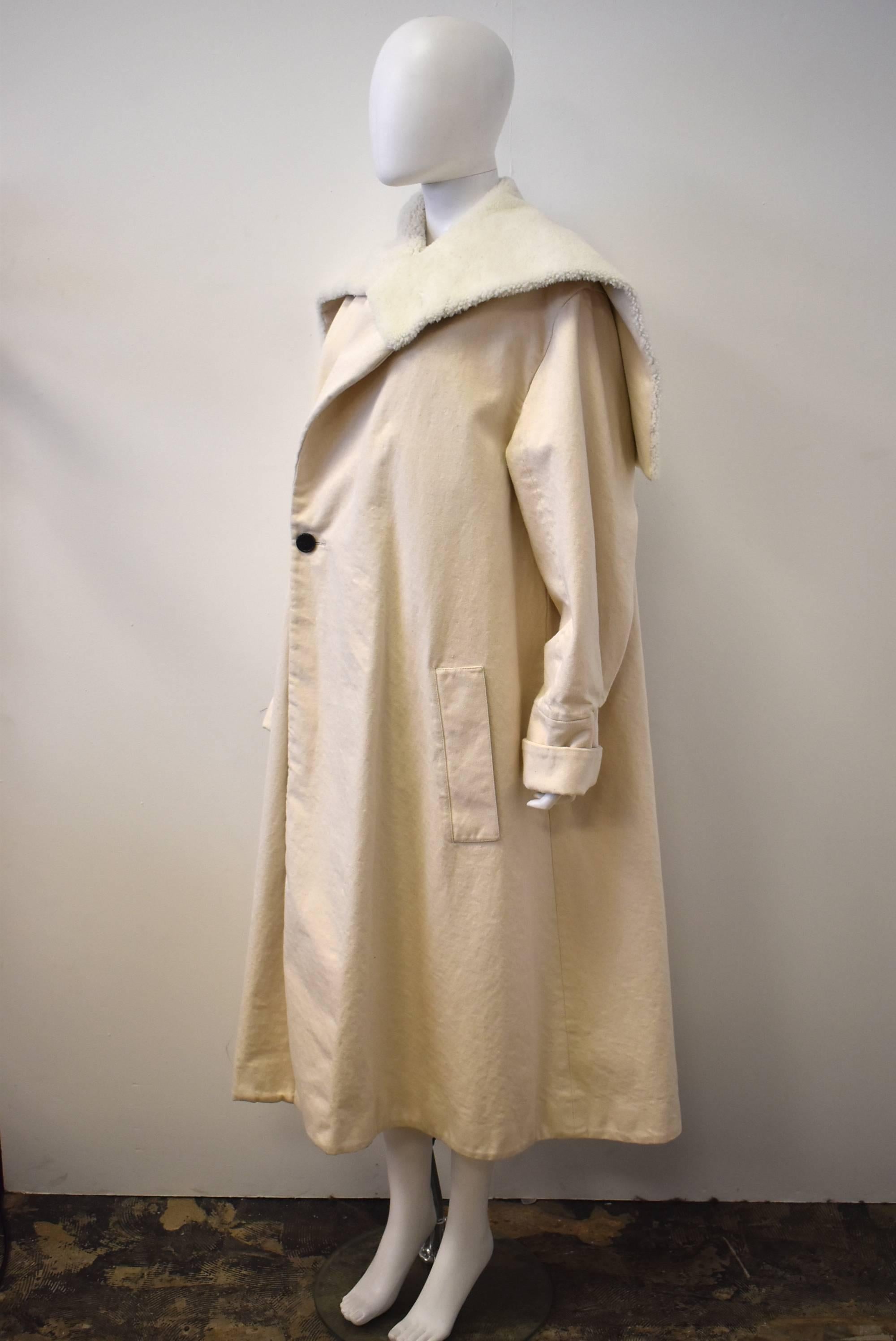 A beautiful, oversize cream cotton coat by French luxury brand Loewe designed by J.W. Anderson. The coat is made from a canvas cotton twill with a large shearling collar, button fastening and two pockets at the hip. The shape of the jacket creates