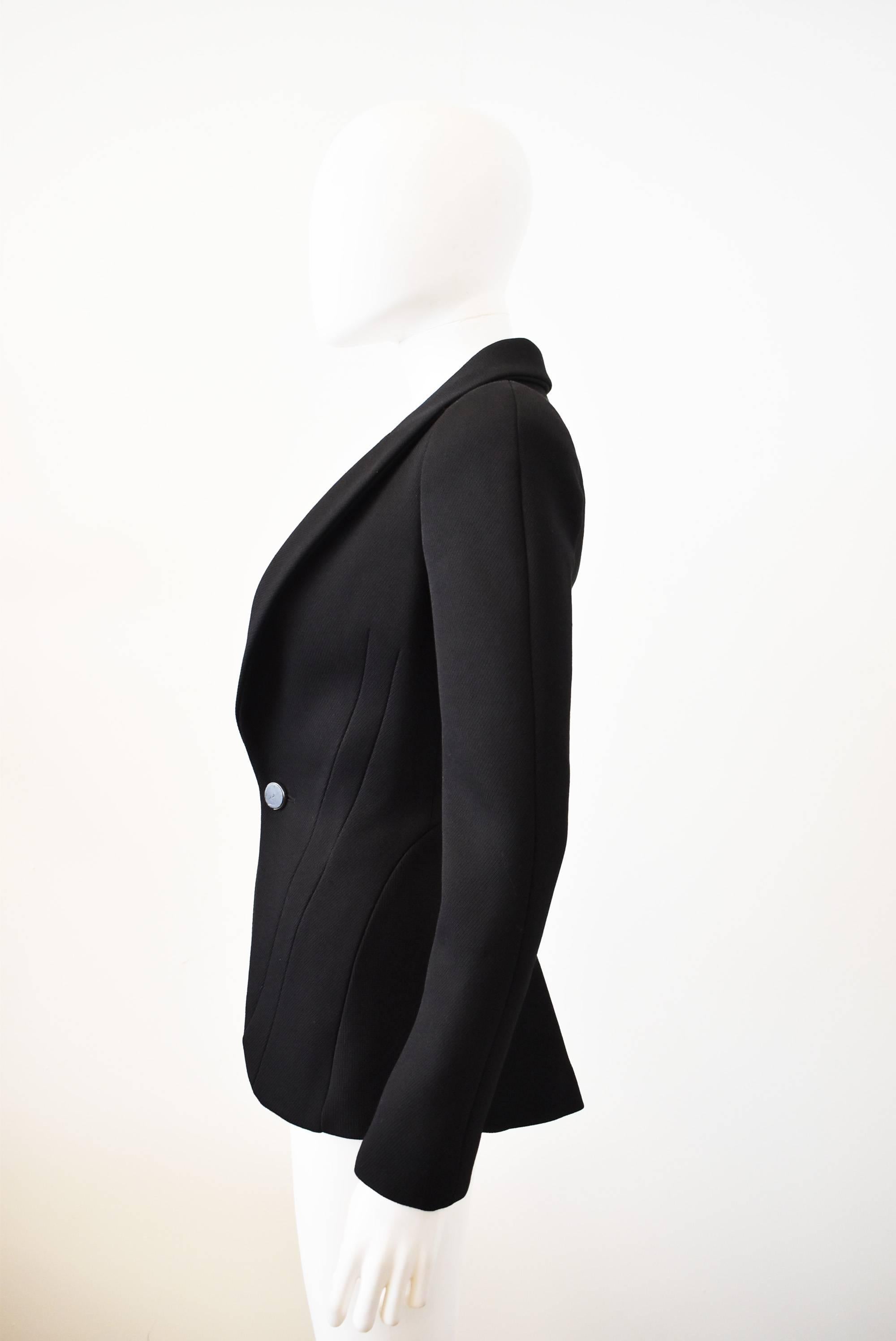 A beautiful and dramatically tailored jacket by Alexander McQueen. The jacket has an extremely fitted shape with shoulder pads, darts and seams nipping in the waist to create an hourglass silhouette. The jacket has an open front with a single