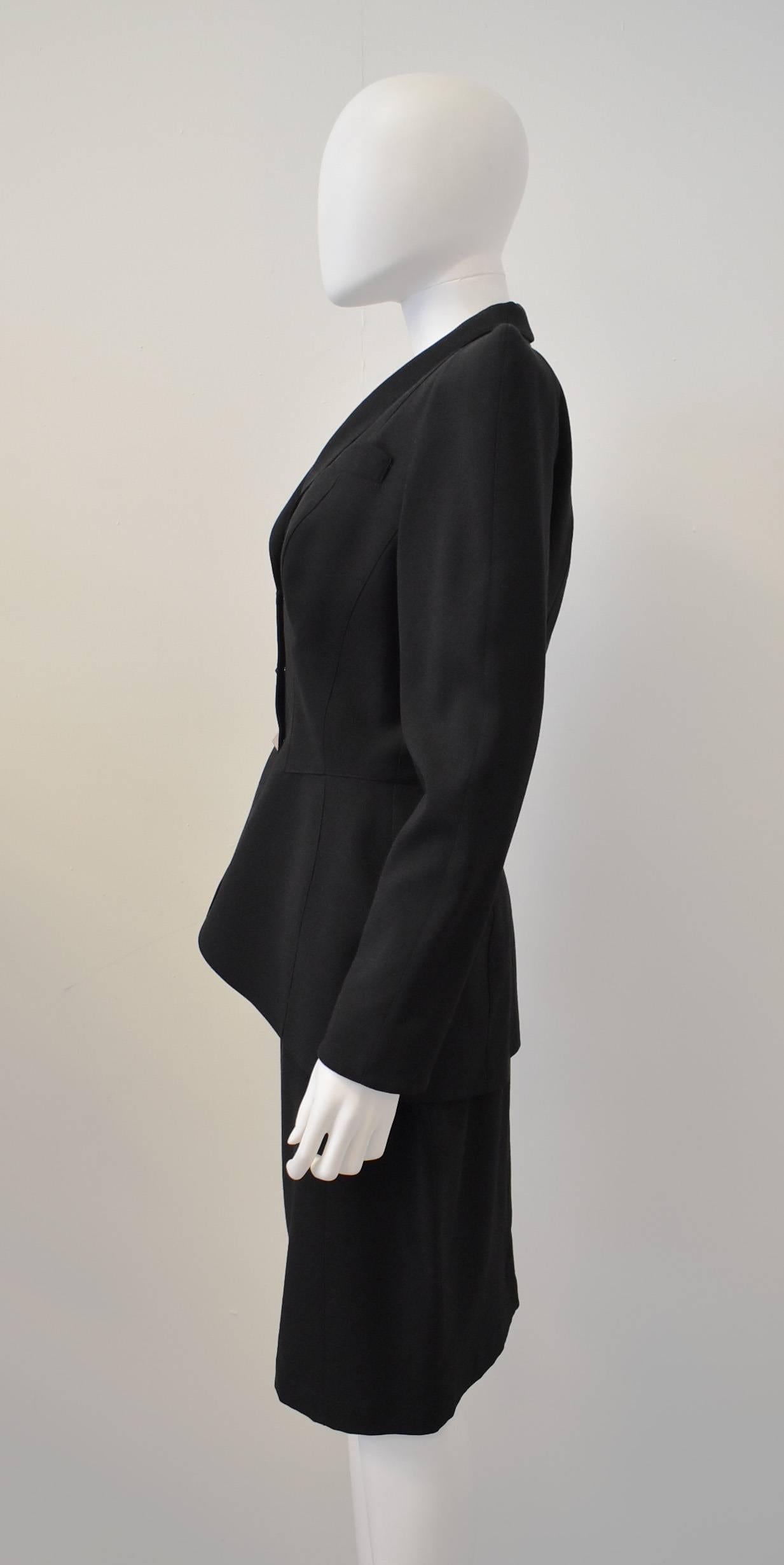 A black vintage skirt suit from legendary designer Thierry Mugler. Featuring his signature exaggerated 1940’s silhouette; with cinched in waist, and large pointed shoulder pads, the suit is a classic Mugler ensemble. Dating from the 1980’s the suit