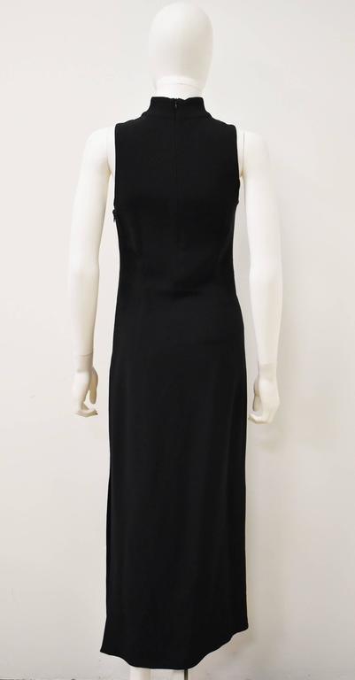 A beautifully elegant black dress by Italian label Miu Miu. The dress has a simple sheath shape, reminiscent of a Cheongsam Chinese dress with a high neck and slit on the left side. It has two zip fastenings along the side and neckline. 
The dress