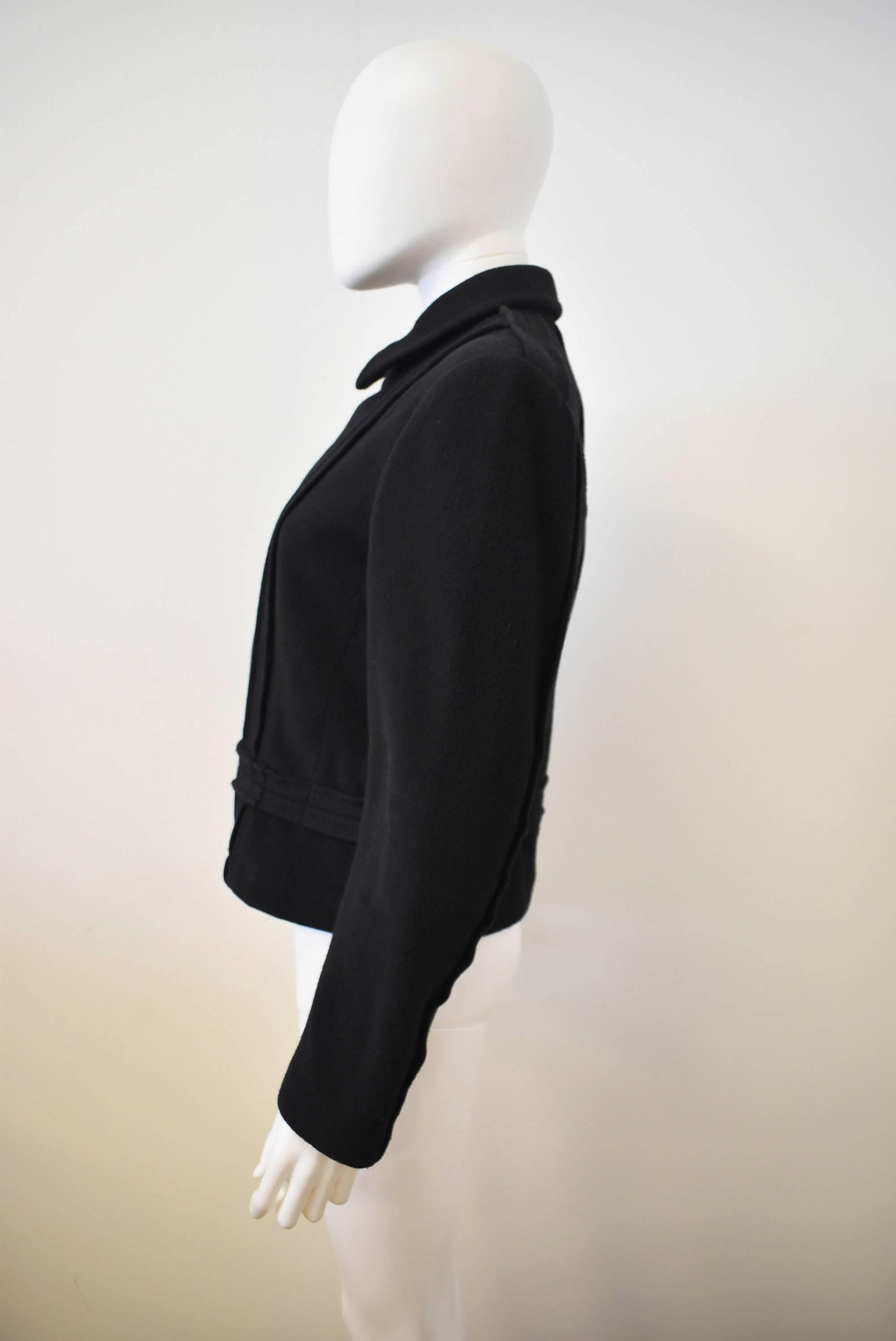 A black Comme des Garçons jacket with a cropped shape and off-centre fastening zip. The jacket also features reversed seam details which create a vertical line across the left chest, and centre back and a horizontal seam along the waist. There are