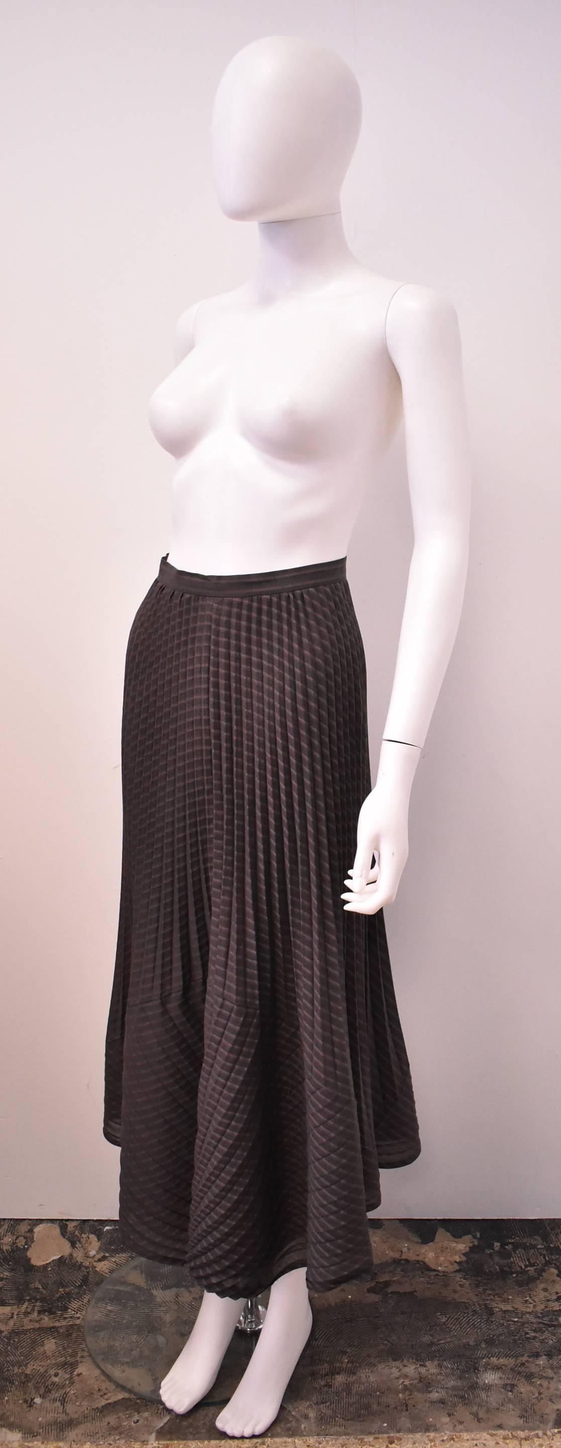 A brown striped long skirt from Issey Miyake’s White Label line. The skirt uses Miyake’s unique heat-pleating technique to create a multi-directionally pleated skirt. The top part of the skirt has vertical pleats with changes in direction at the