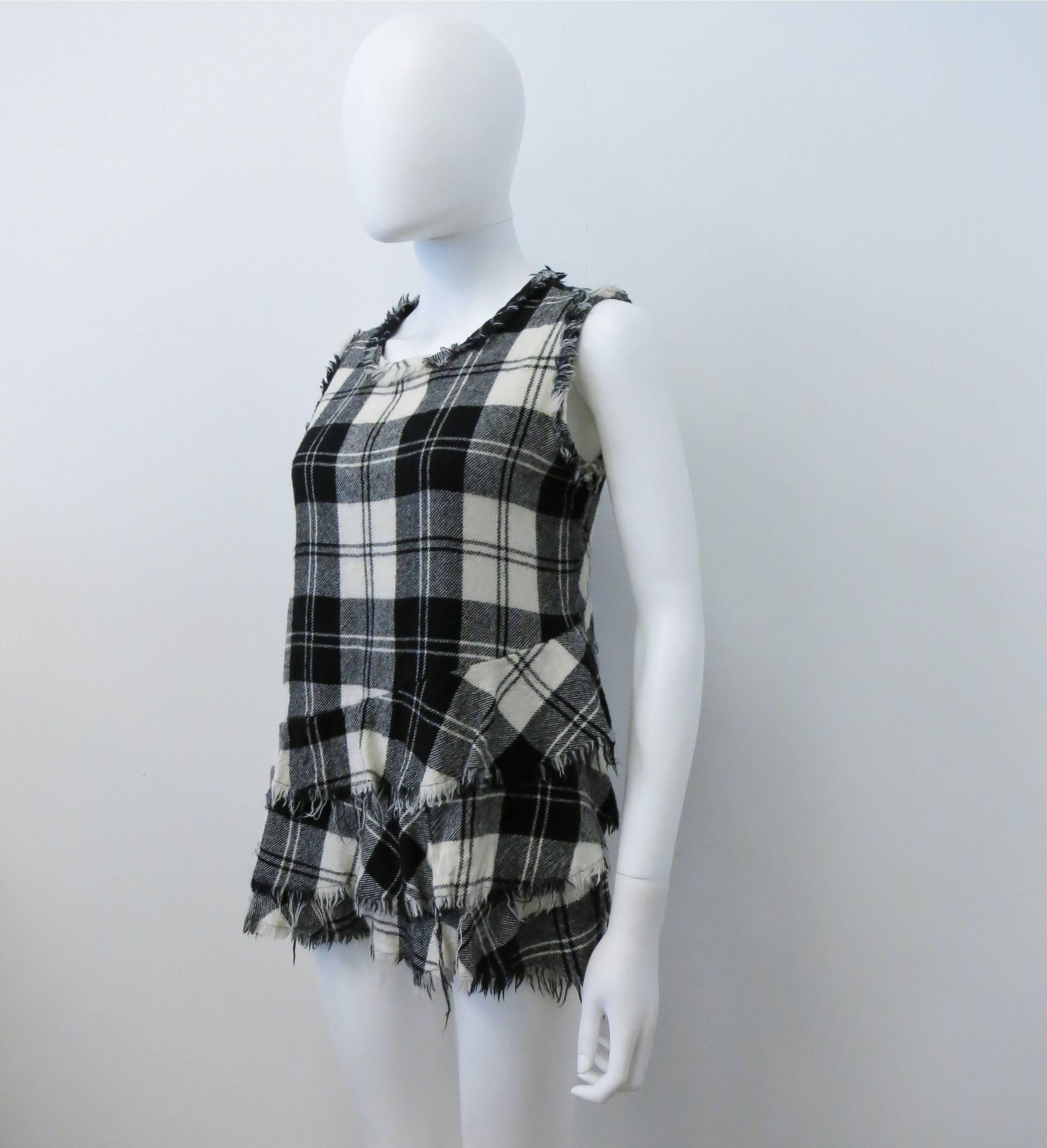 A black and white plaid wool vest top from the 2004 Junya Watanabe MAN line. The sleeveless top has a simple shape but is given a Junya Watanabe, punk twist with raw, frayed edges and a circular frill that goe around the bottom half of the top