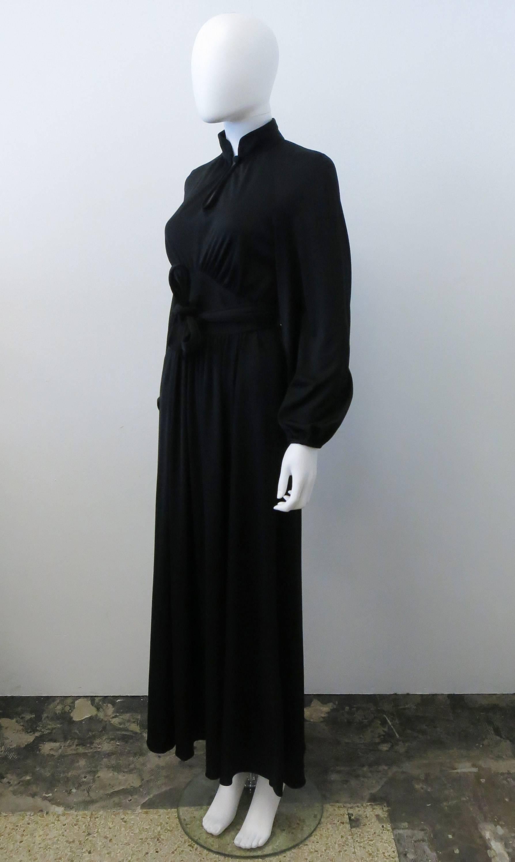 A 1970s black vintage bell-sleeve dress by British label Quorum from designer Marie France. The dress has a beautiful and iconic 70’s silhouette with long sleeves, mandarin collar and keyhole neckline, fitted waist and soft flowing pleats in the