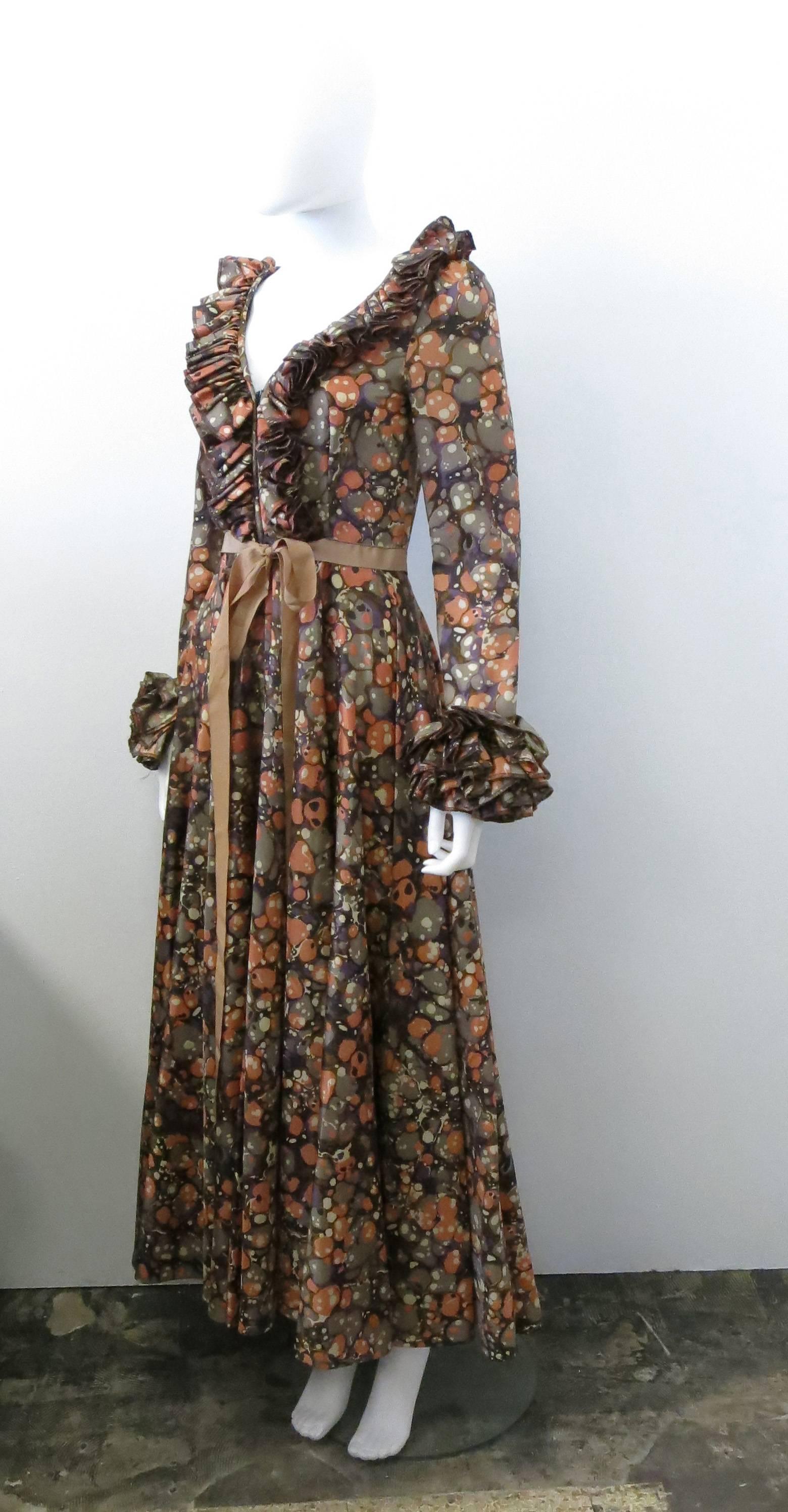 A multicolour, psychedlic print vintage  dress by British label Jean Varon dating from the 1970’s.The dress has a beautiful period silhouette, with ruffled V-neck collar, cinched waist, tie belt and long sleeves with ruffle cuffs, The skirt falls to