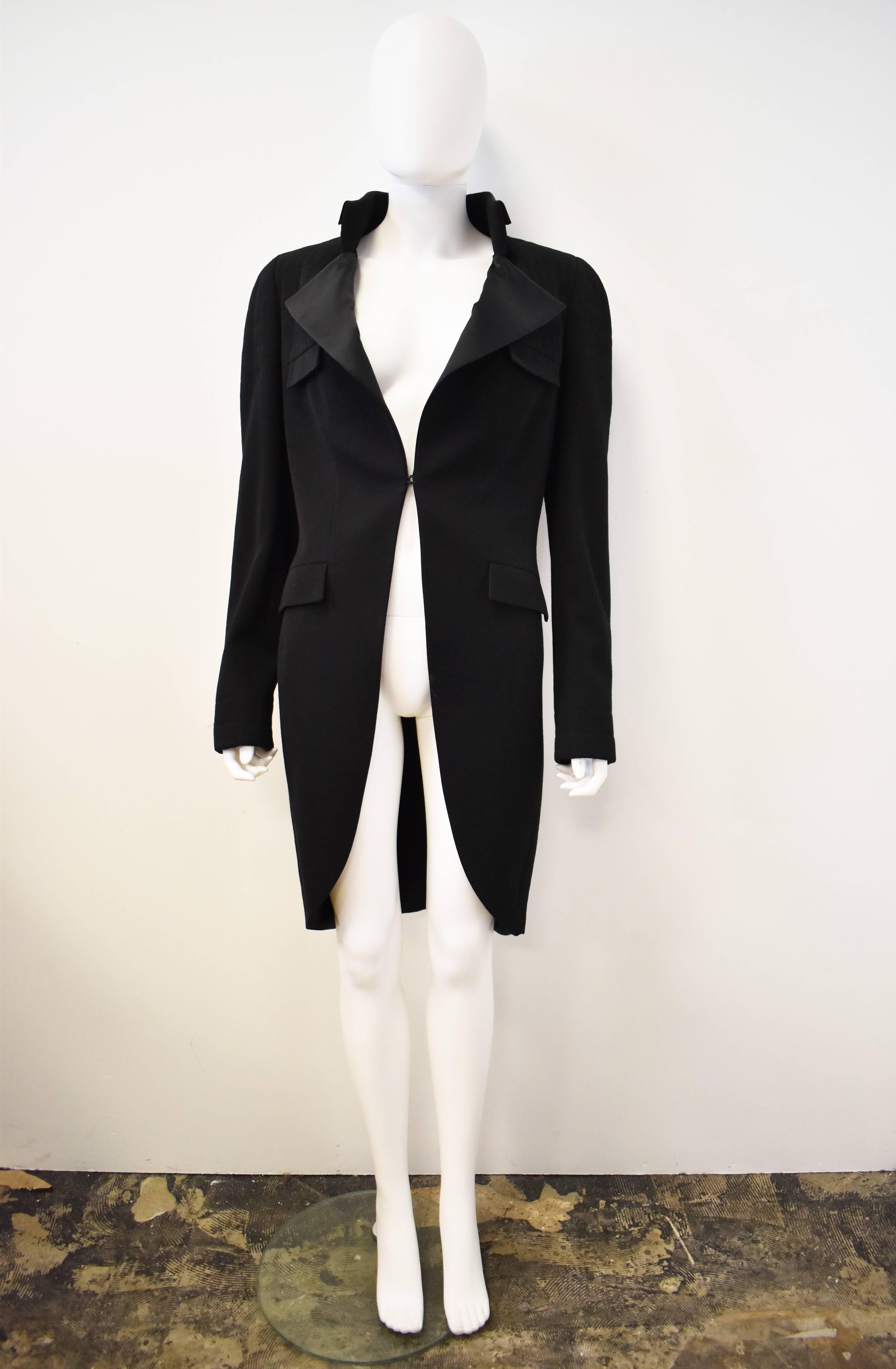 A classic black tuxedo Coat from Chanel’s Autumn Winter 2006 collection. The jacket has a V-neck opening with a small standing collar and triangular lapels. There is a single hook and eye fastening at the waist. The jacket then tapers to a curved