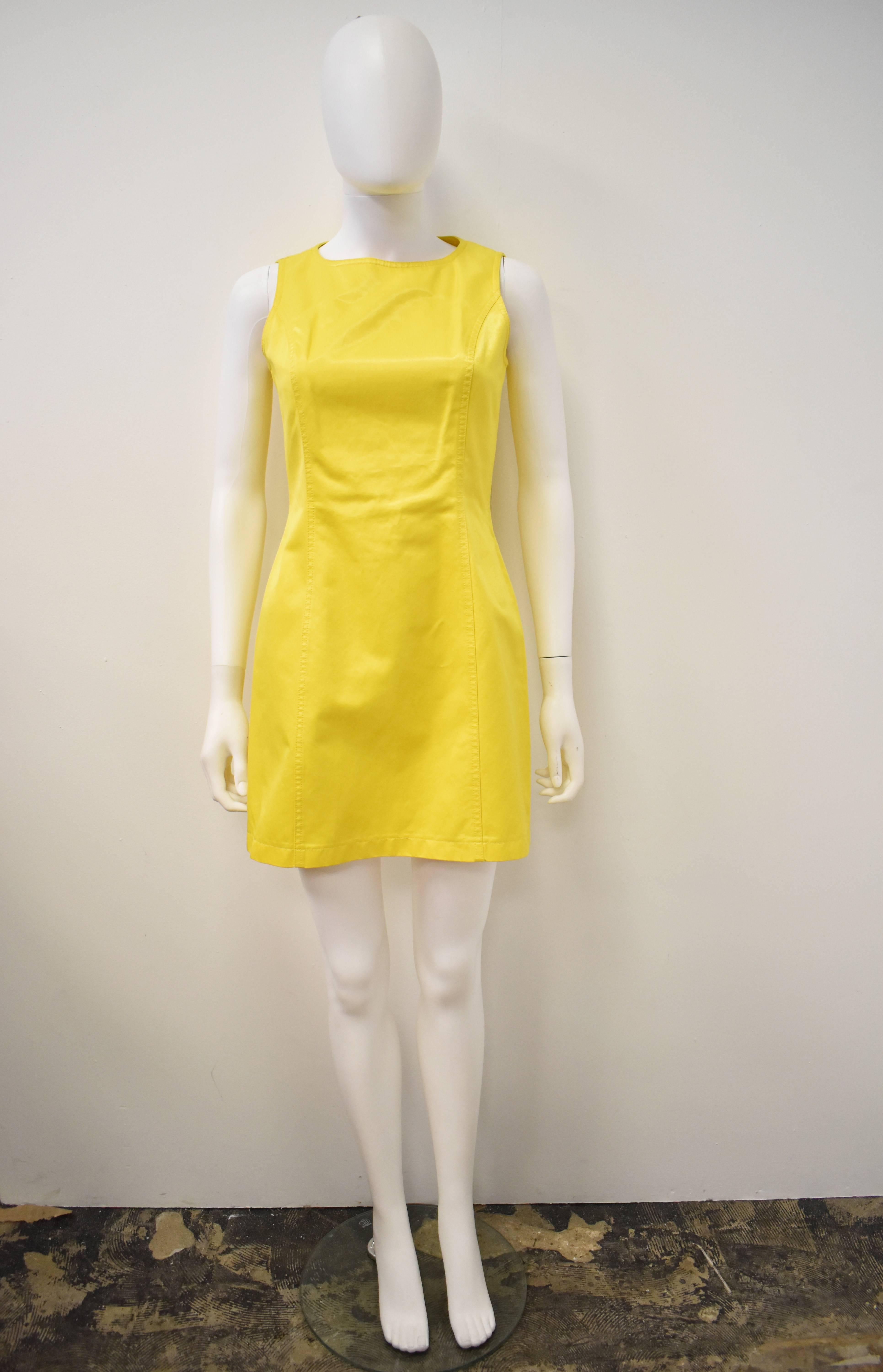 A bright and fun yellow mini dress from the 90’s by Moschino. The dress is sleeveless and has a classic 60’s mini dress shape with fitted waist and slight flair to the skirt. There are two light pen marks on the back of the dress, please see the