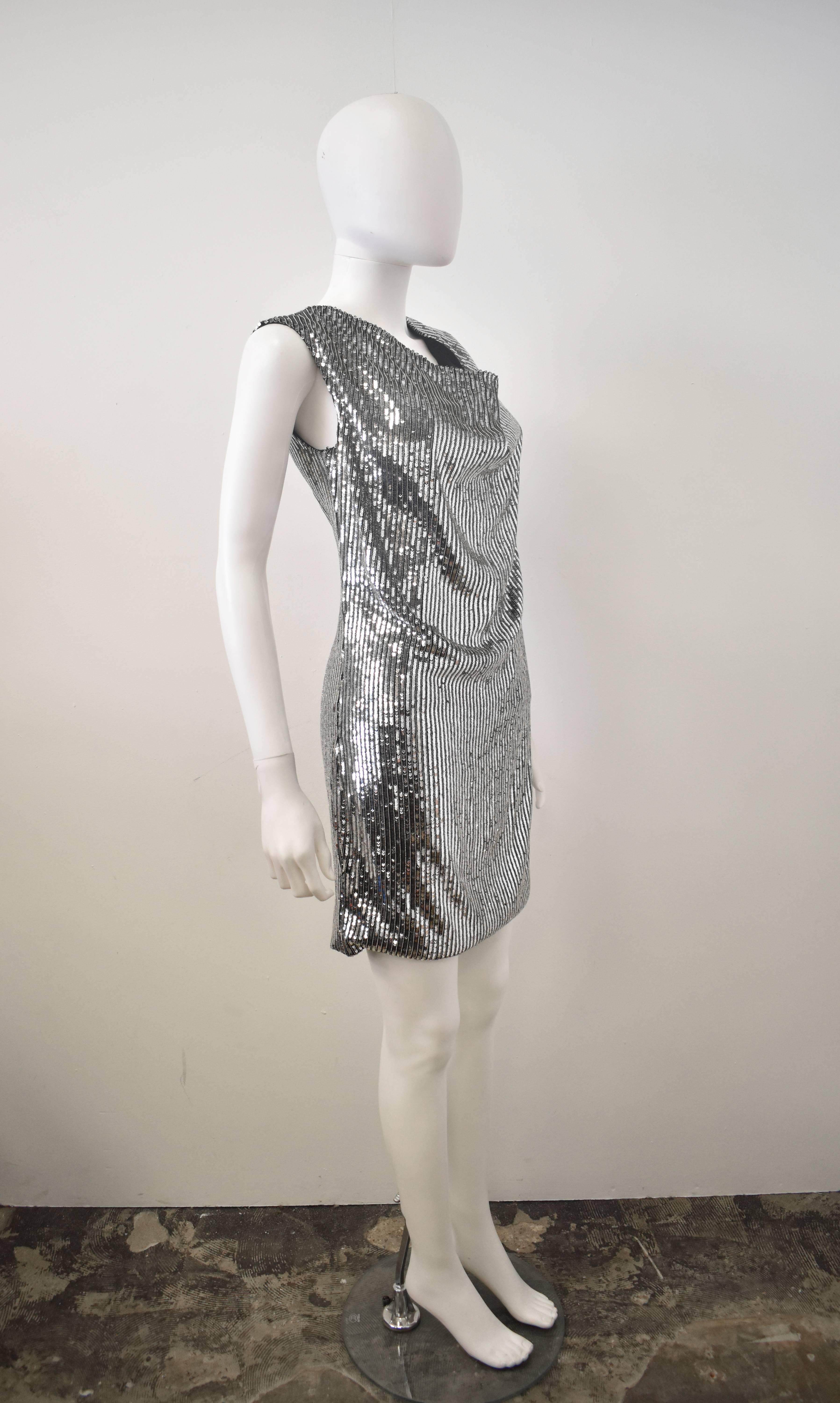A brand new and unworn Saint Laurent by Hedi Slimane silver sequin and beaded dress. The dress has a simple, sleeveless, straight shape, with a short skirt length and a cowl draped neckline. The dress is made from 100% silk with silver sequin and