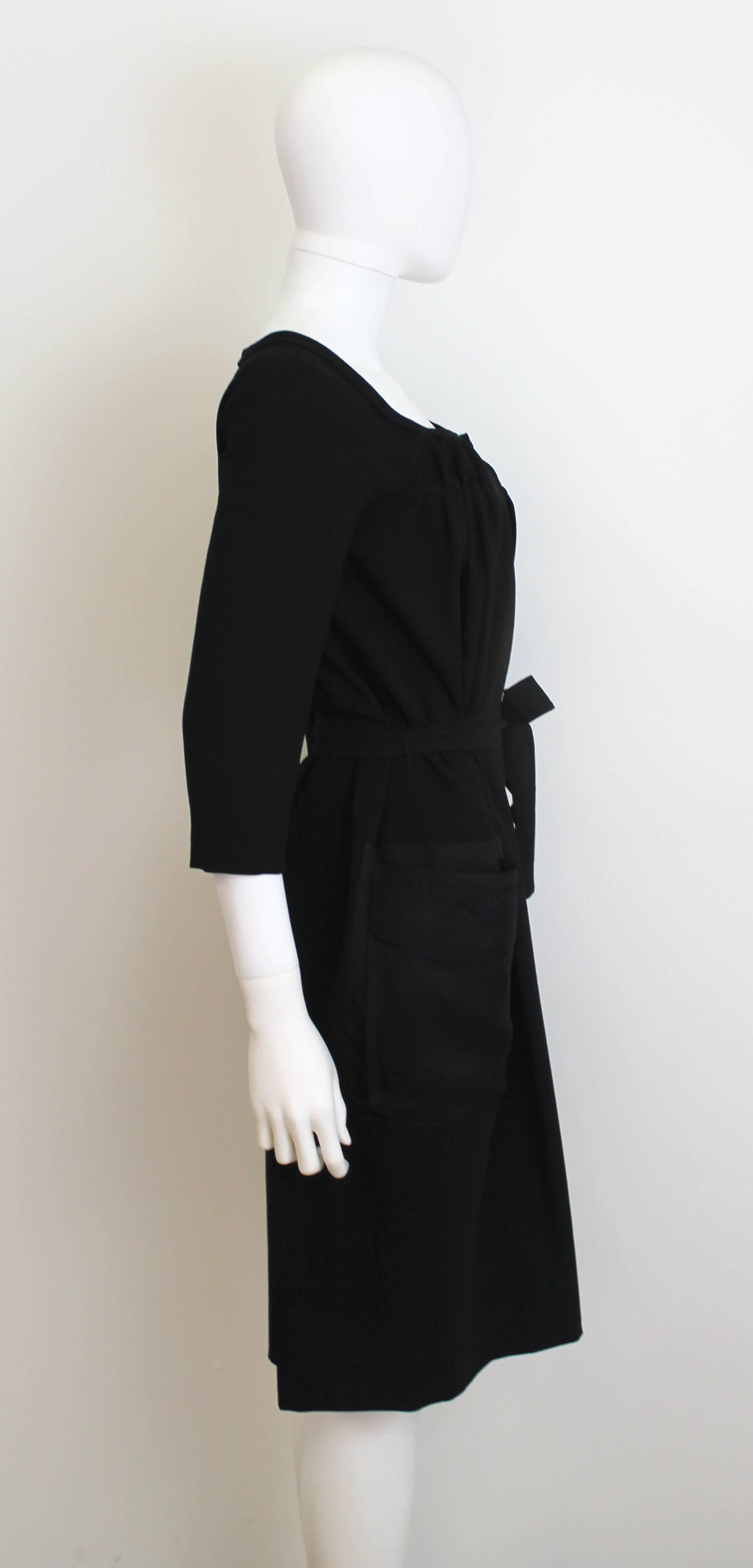 Classic and elegant Christian Dior black dress with sheer pockets. Features a tie-belt and gathering at the bust and neck-line. Can also be worn as a coat.