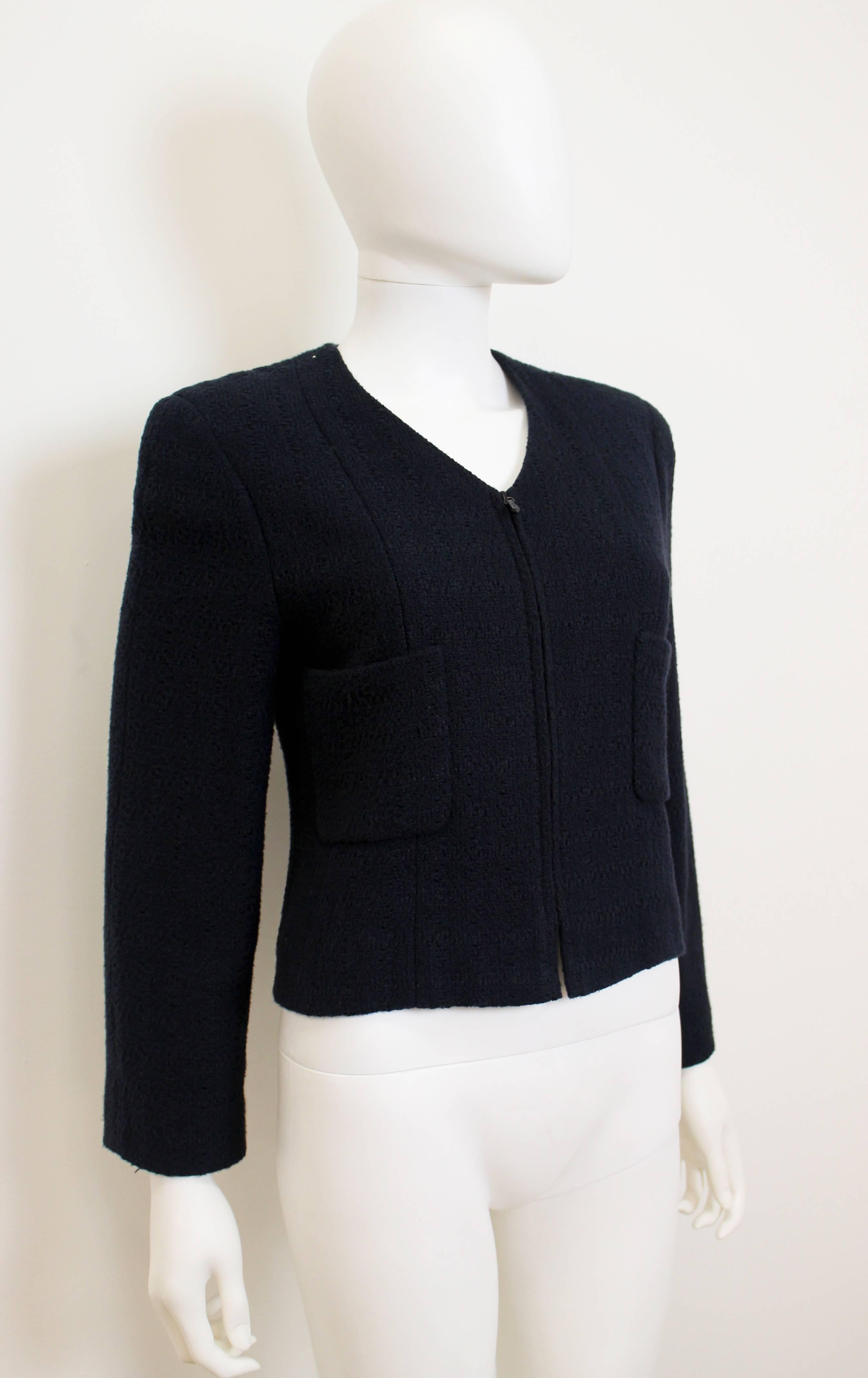 Classic Chanel cotton jacket in navy blue. Features two patch pockets on the waist, as well as a faint check print. Has an invisible zip closure, with Chanel branding on the zipper-tab.