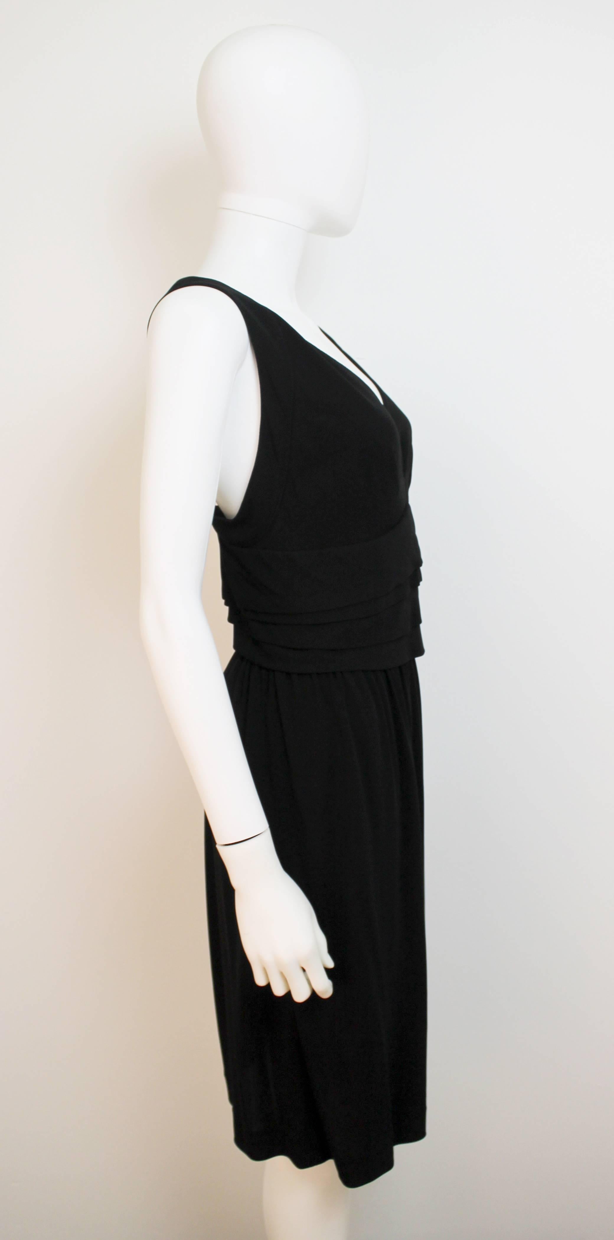 Classic little black evening dress with low back and neckline. The waistline is highlighted by horizontal fixed layers of fabric. 