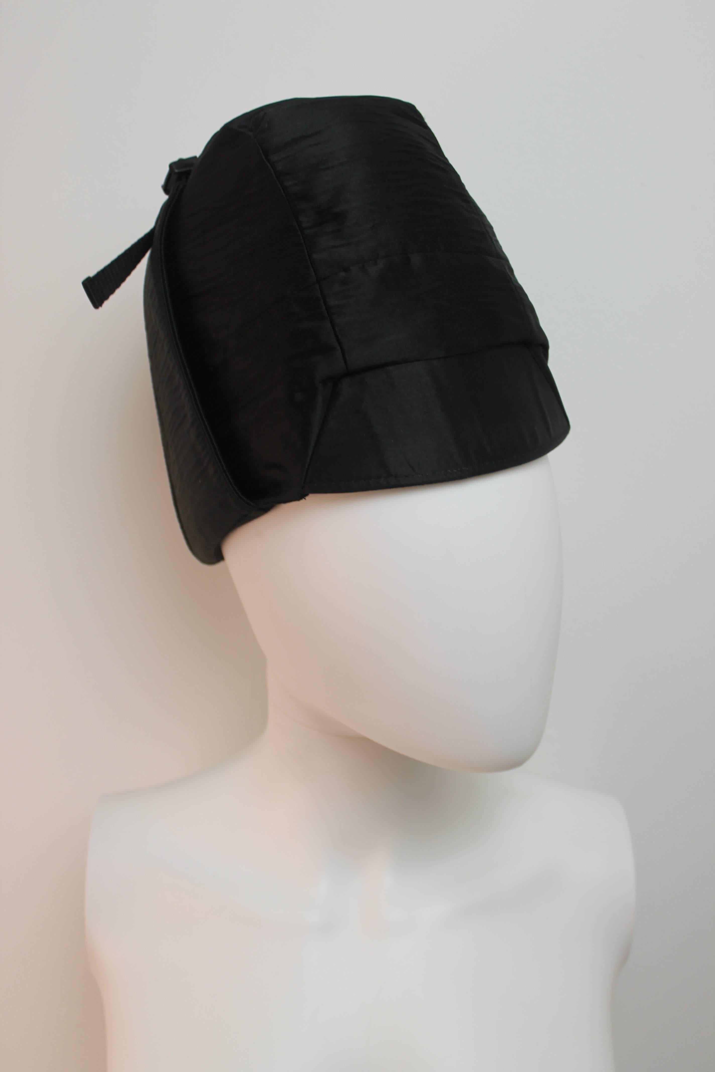 Luxurious Prada black hat with two wind straps and silver fastening under the chin.