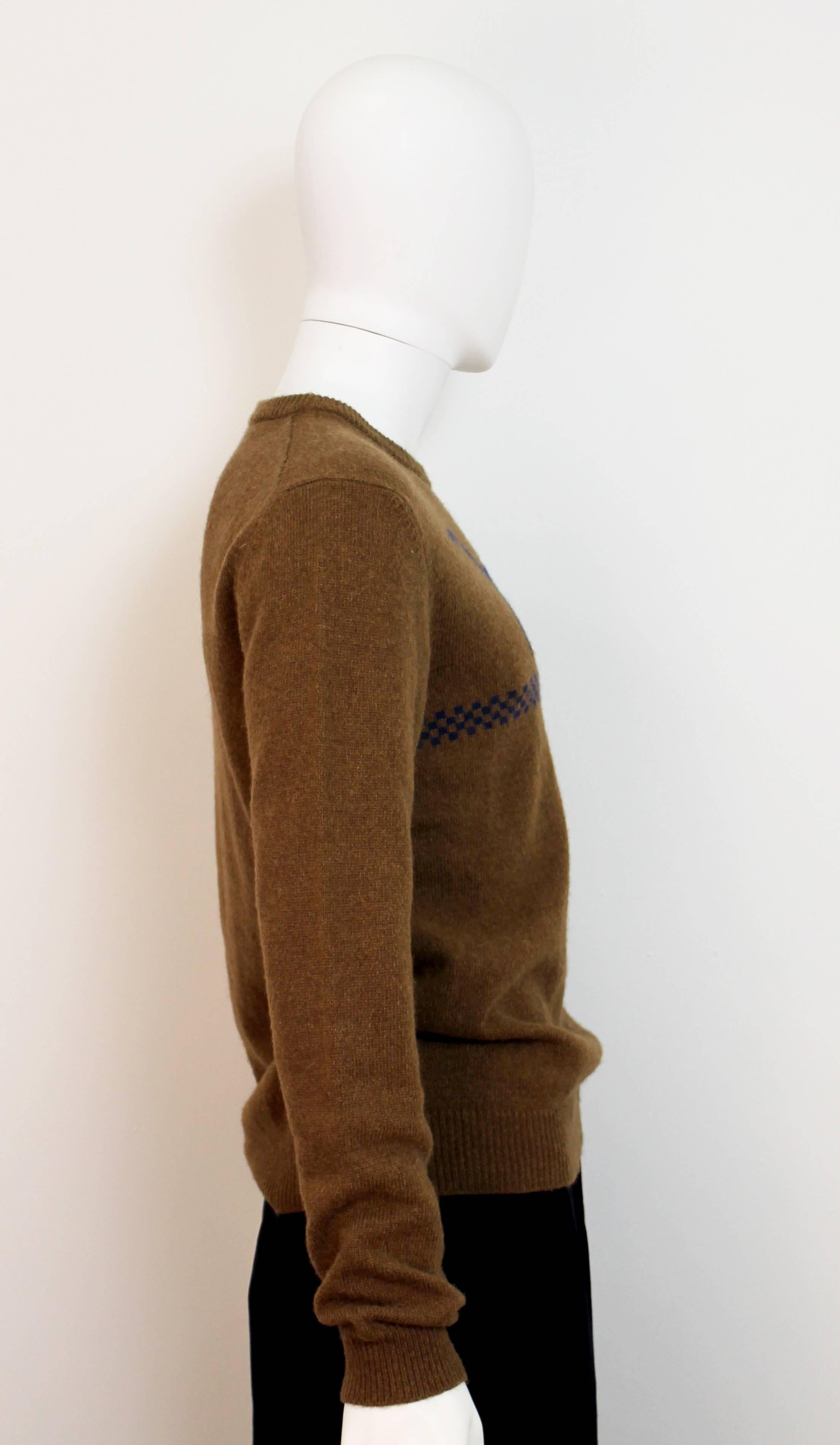 Jil Sander brown jumper from their Autumn/Winter 2012 collection. Features a blue dinosaur and checked motif. A great example of classic Raf Simons style.