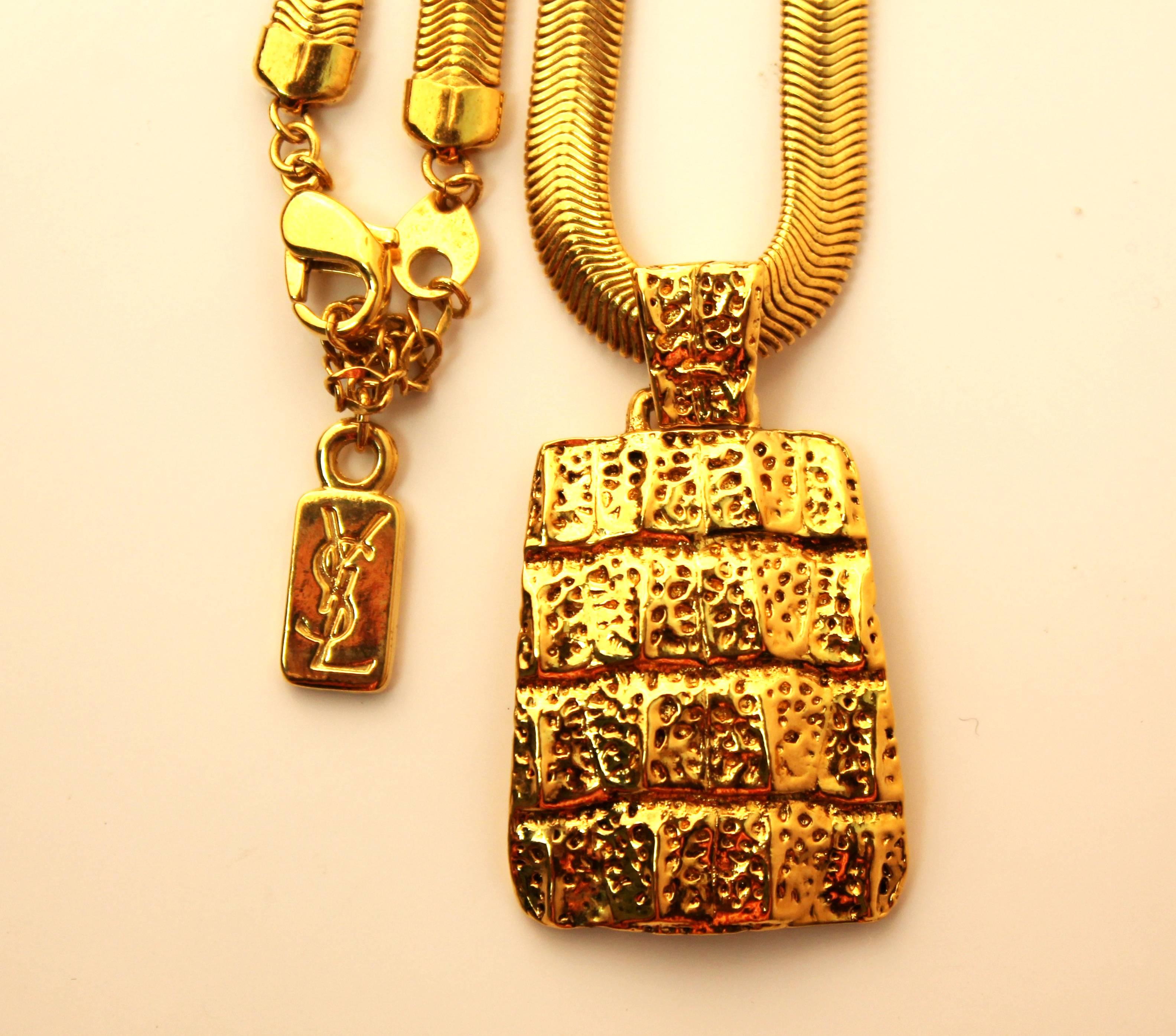 Classic vintage Yves Saint Laurent necklace with a rectangular-shaped hanging pendant. Features a crocodile  texture and a flat serpentine chain. Comes with original box.