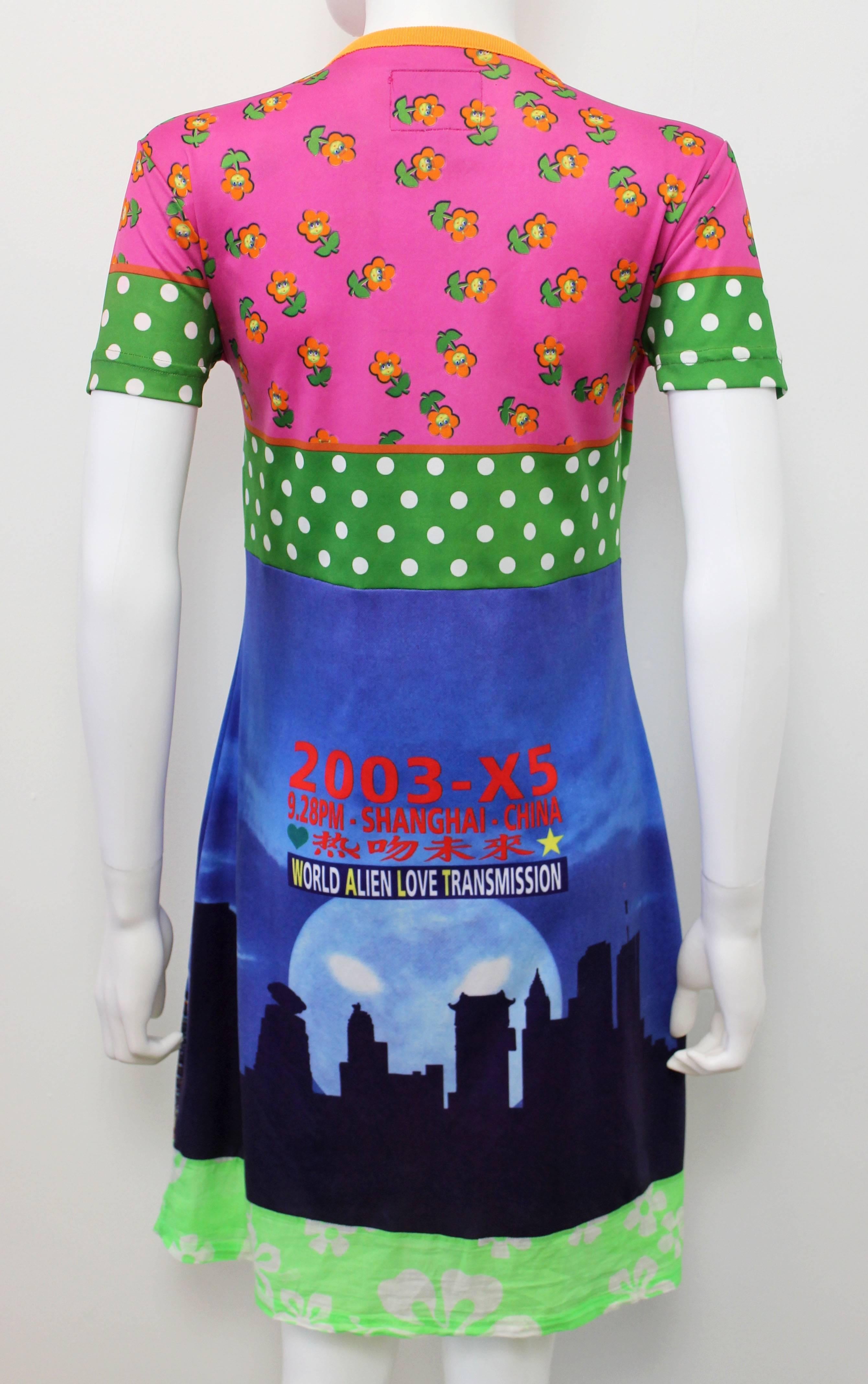 This 2003 short sleeve printed playful jersey dress features a contrasting mix of different printed panels, a pink flower print, green polka dot print, a neon hibiscus printed cotton panel and a detailed digital printed image of a Chinese skyline