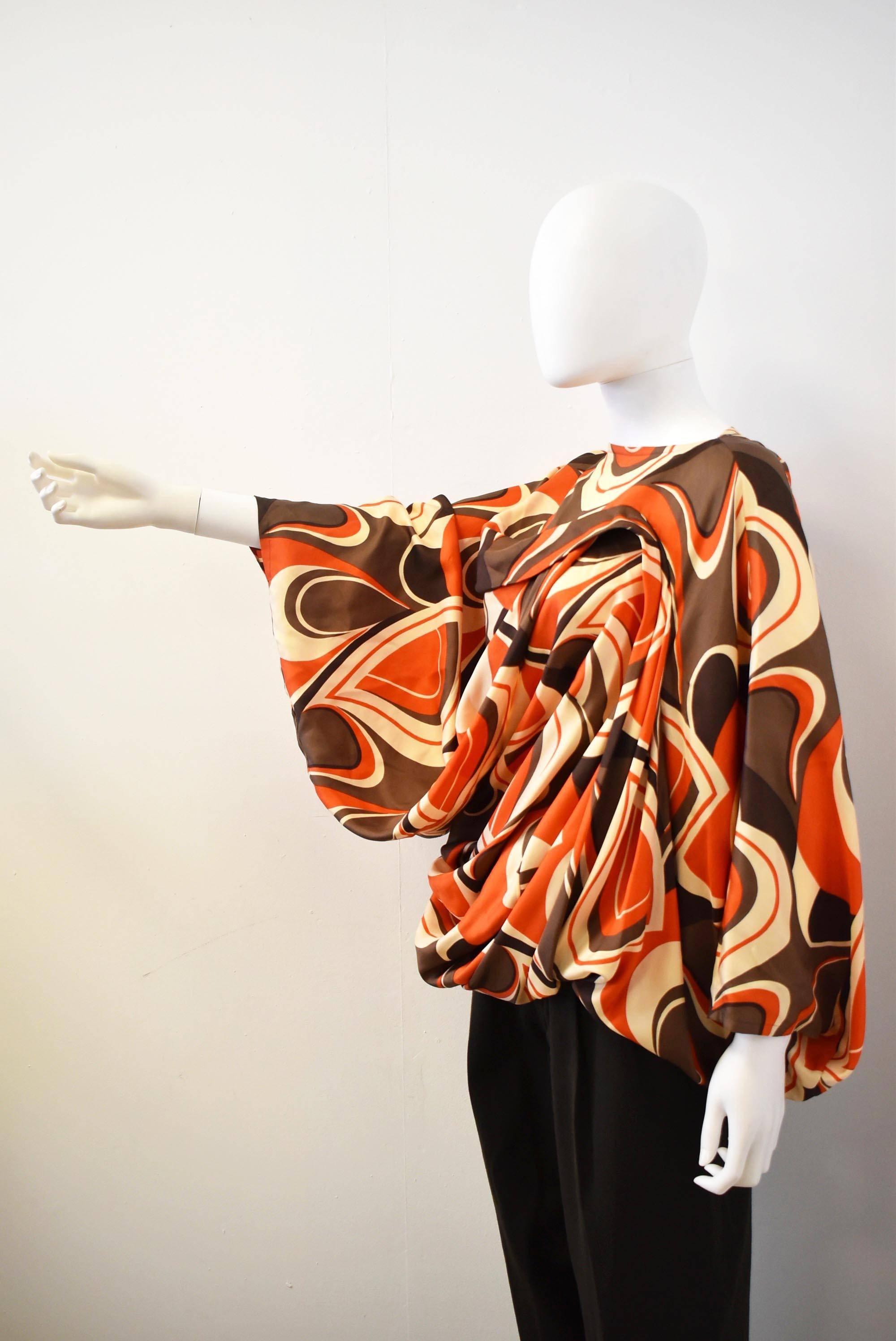 A beautiful silk batwing top with psychedelic orange, brown and beige print by Junya Watanabe. The unusual top has oversized sleeves, and a curved, twisted shape that creates drapes and folds that adapt to the form and movement of the body. The top
