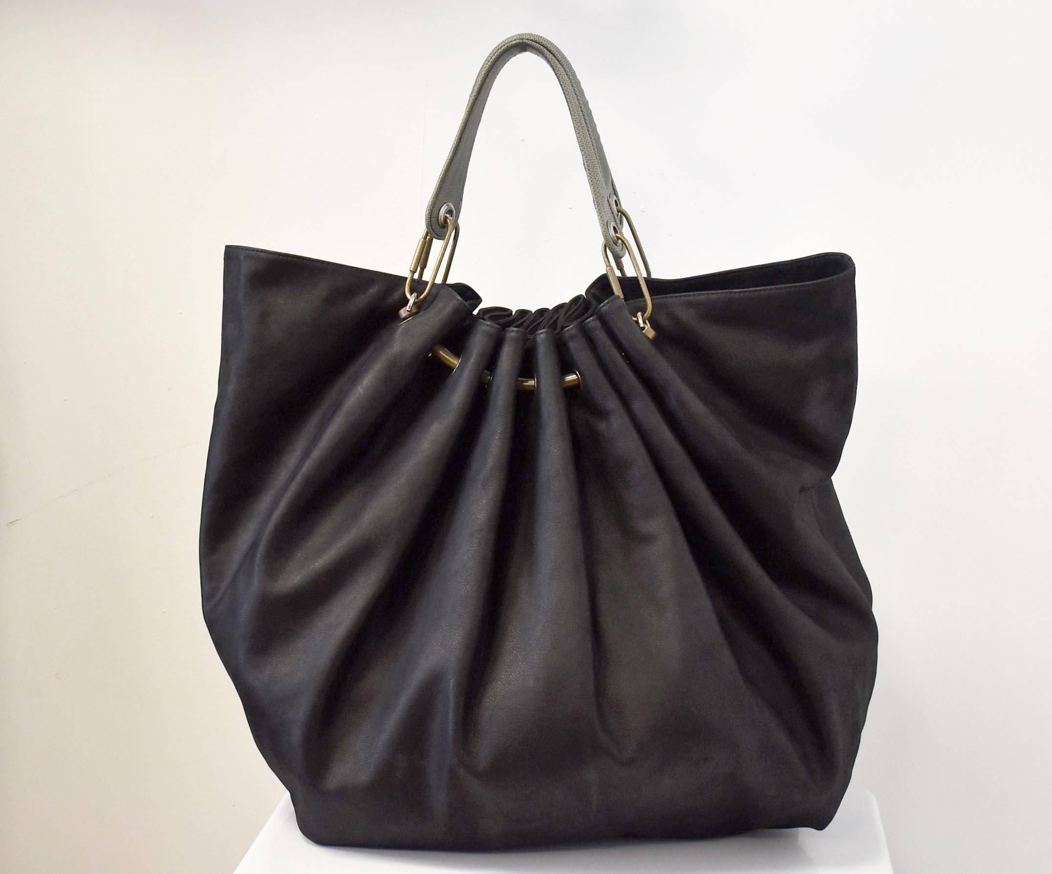 A luxurious black oversize leather handbag from French design house Lanvin. The ‘sack’ shaped handbag has two green leather handles and brass rivets and hardware across the opening that creates soft pleats in the body of the bag. The beautiful and