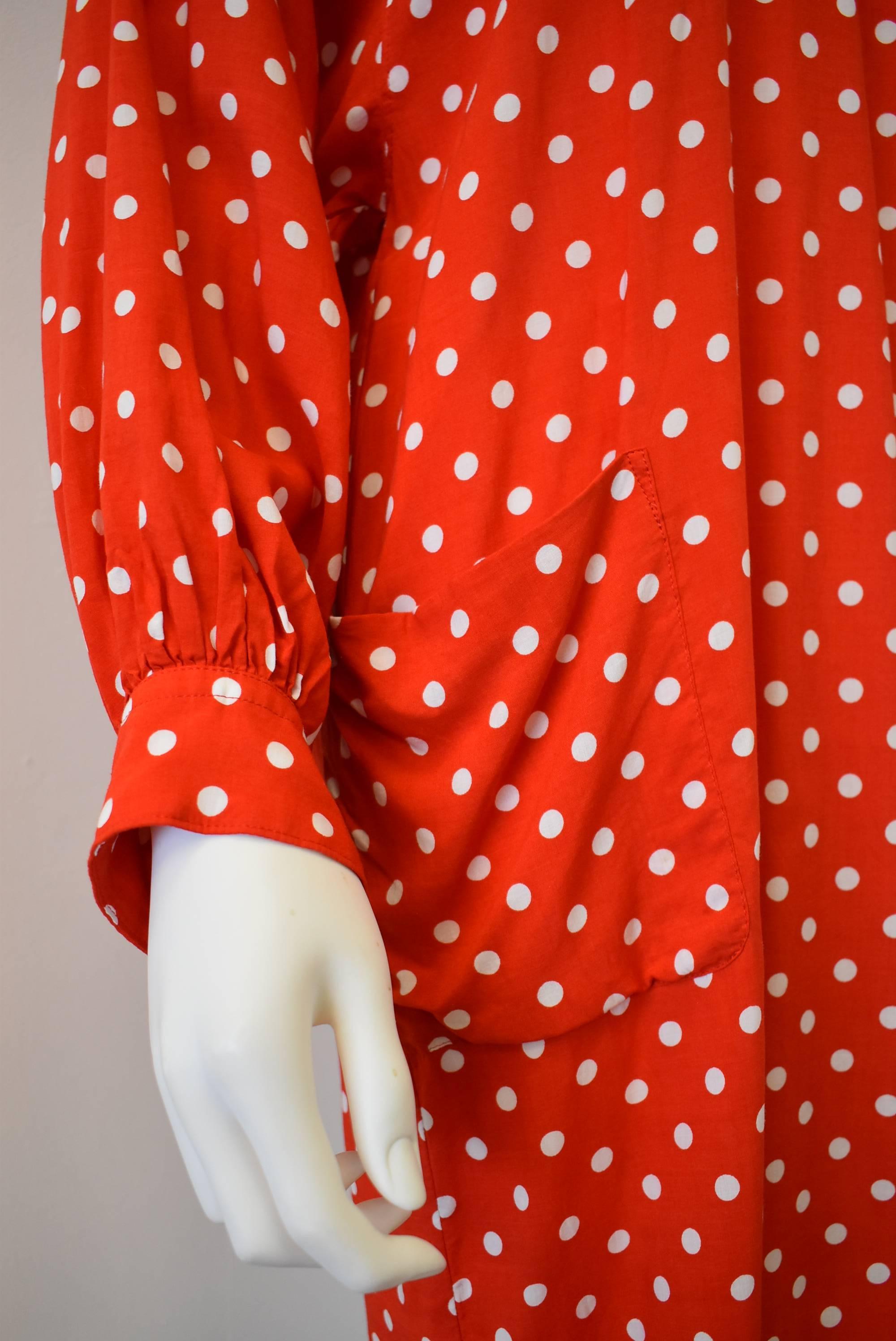 A red and white polka dot ‘Minnie Mouse’ pinafore dress from Comme des Garçons. The dress has a Peter Pan collar, pocket on the front and a concealed inside pocket. The pinafore dress is designed to be worn over clothing and has two ribbon ties at