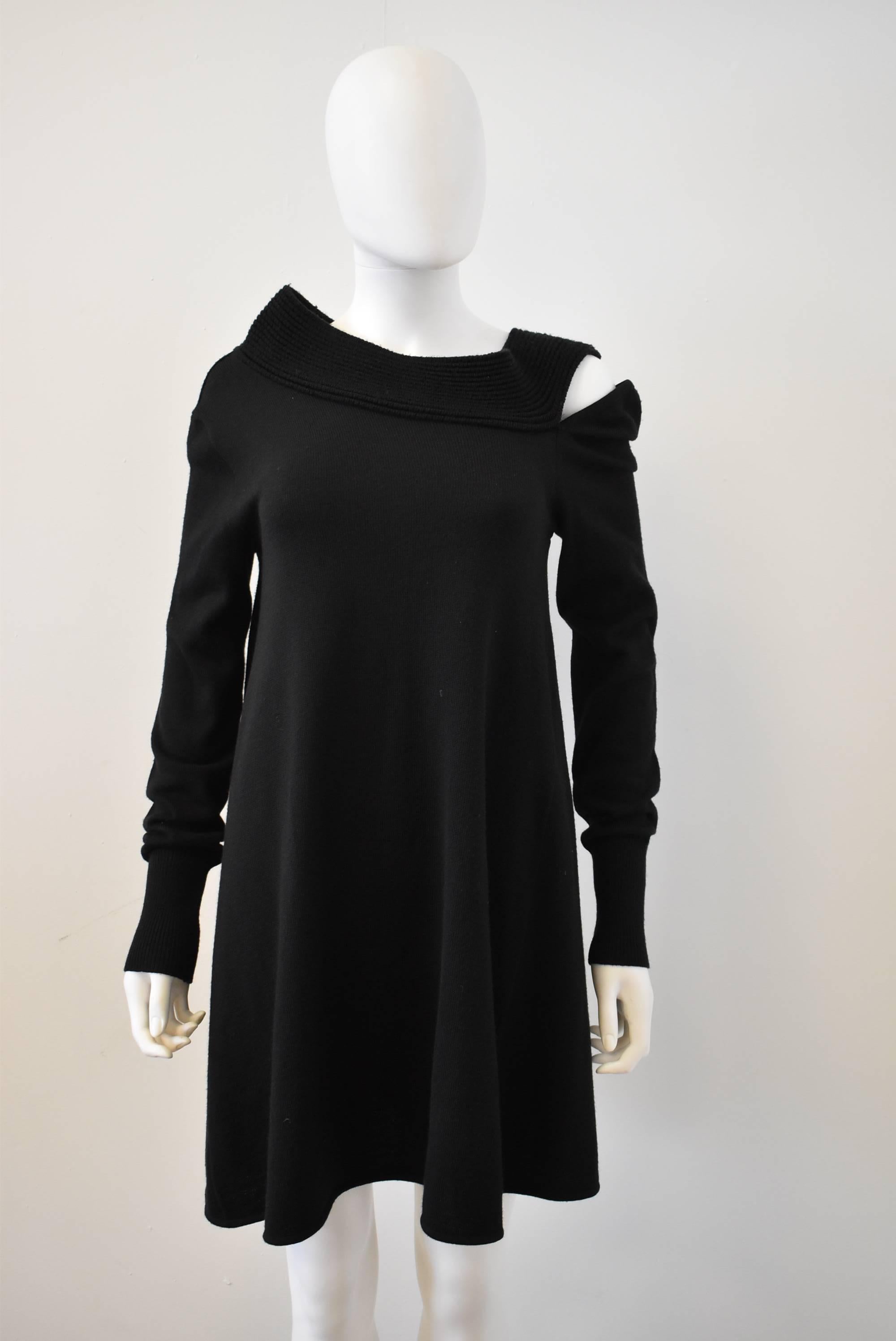 A beautiful black knit dress from Balenciaga. The asymmetric neckline has a ribbed texture which can be worn as a funnel neck or pulled down to reveal the shoulders. The left arm has a cold shoulder opening for a twist on a simple knit dress. 