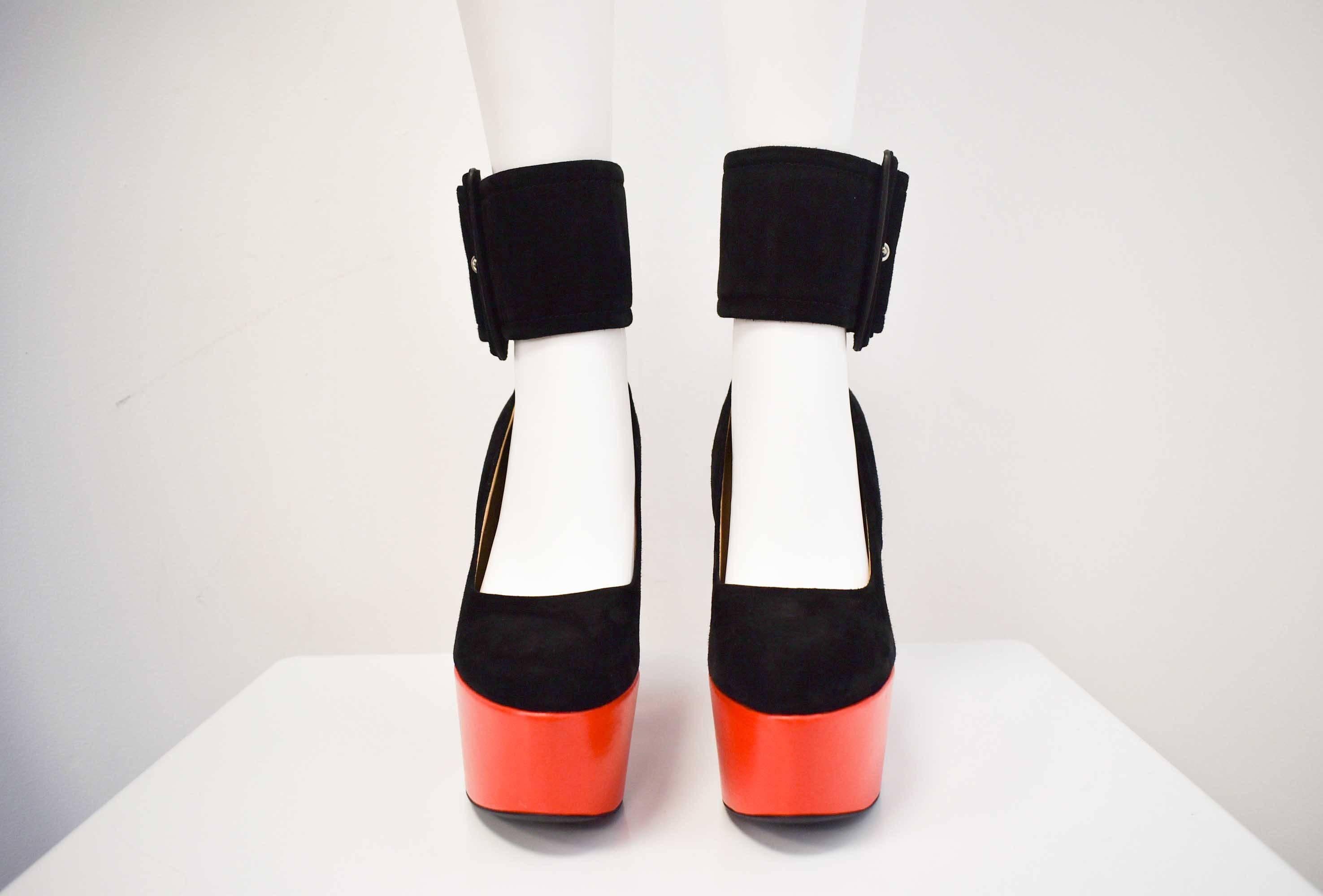 These Gorgeous Celine shoes are from Celine’s Spring Summer 2012 collection. The shoes are made from a soft black suede and the platform is made from a bright red leather. 
The shoes also feature an oversized ankle strap that resembles a cinch