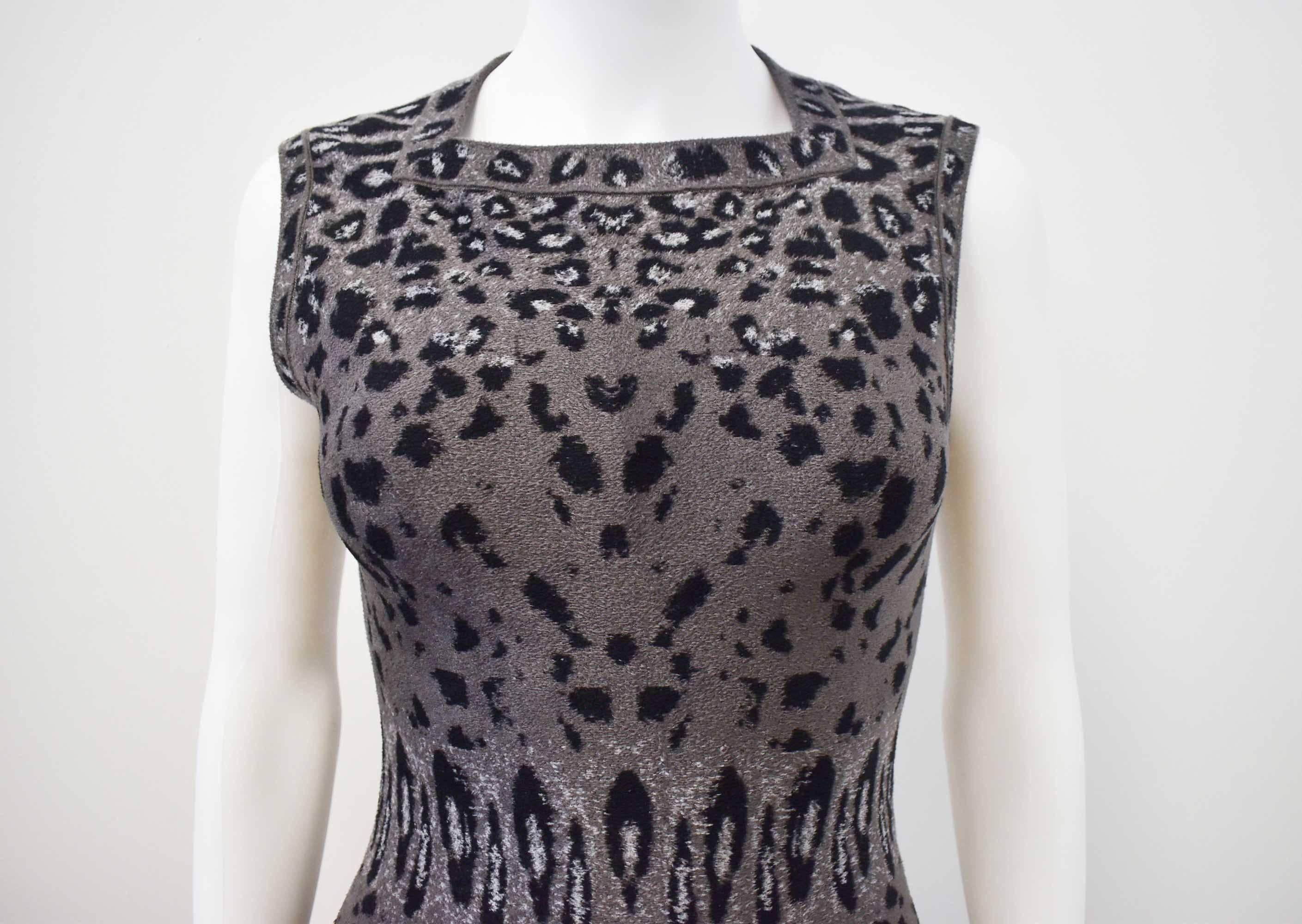 A soft textured, grey, leopard print body con dress from Azzedine Alaia. The dress is sleeveless with a square neckline and a long cut, falling to below the knee. The dress is made from Alaia’s signature stretch material creating a tight, fitted