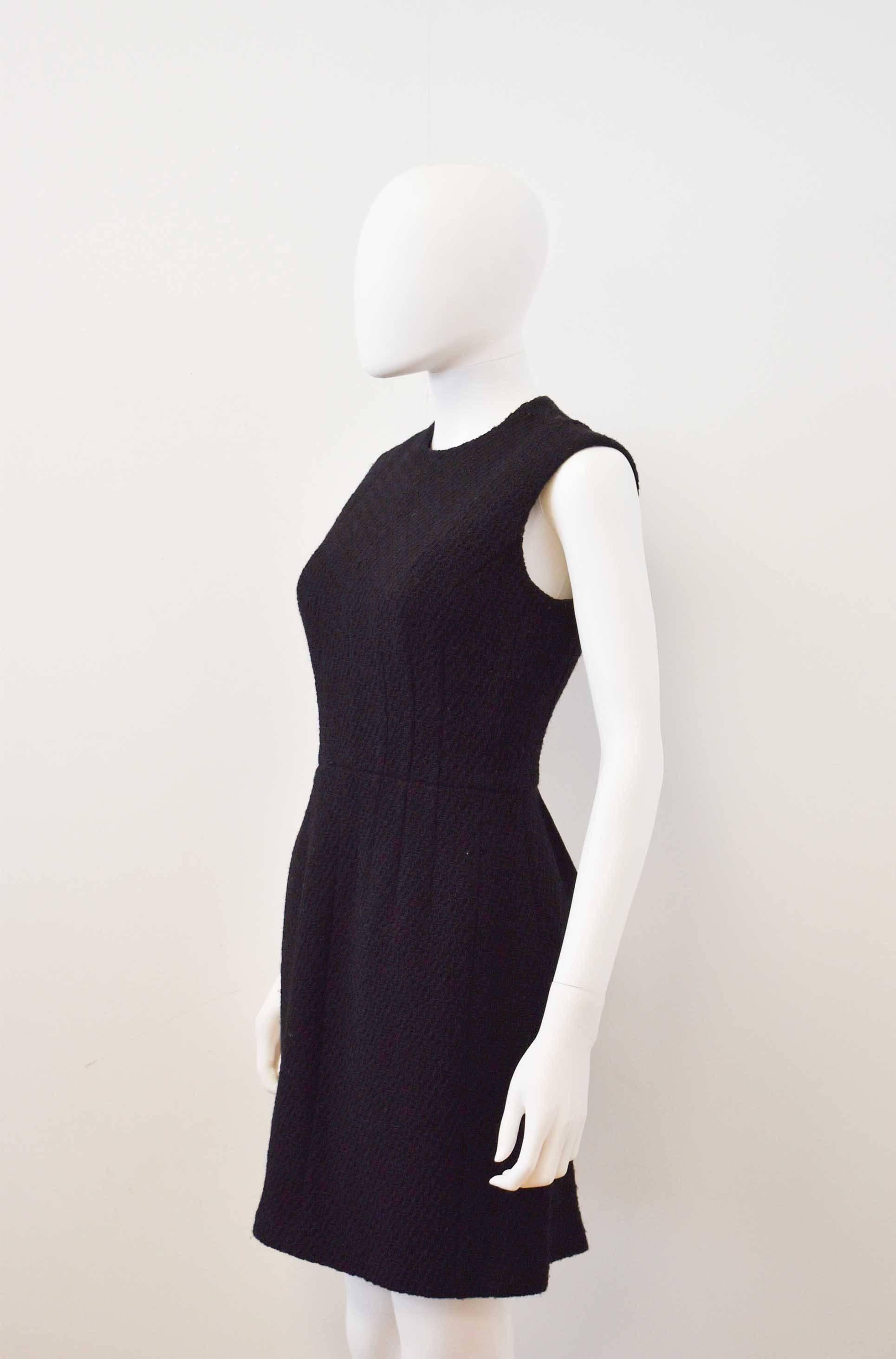 A black boucle wool shift dress by Comme des Garçons designer Junya Watanabe. The sleeveless dress has a simple, classic shift shape and a deconstructed twist with an open ‘apron’ back with a ribbon tie. The dress is 1997 and in excellent condition