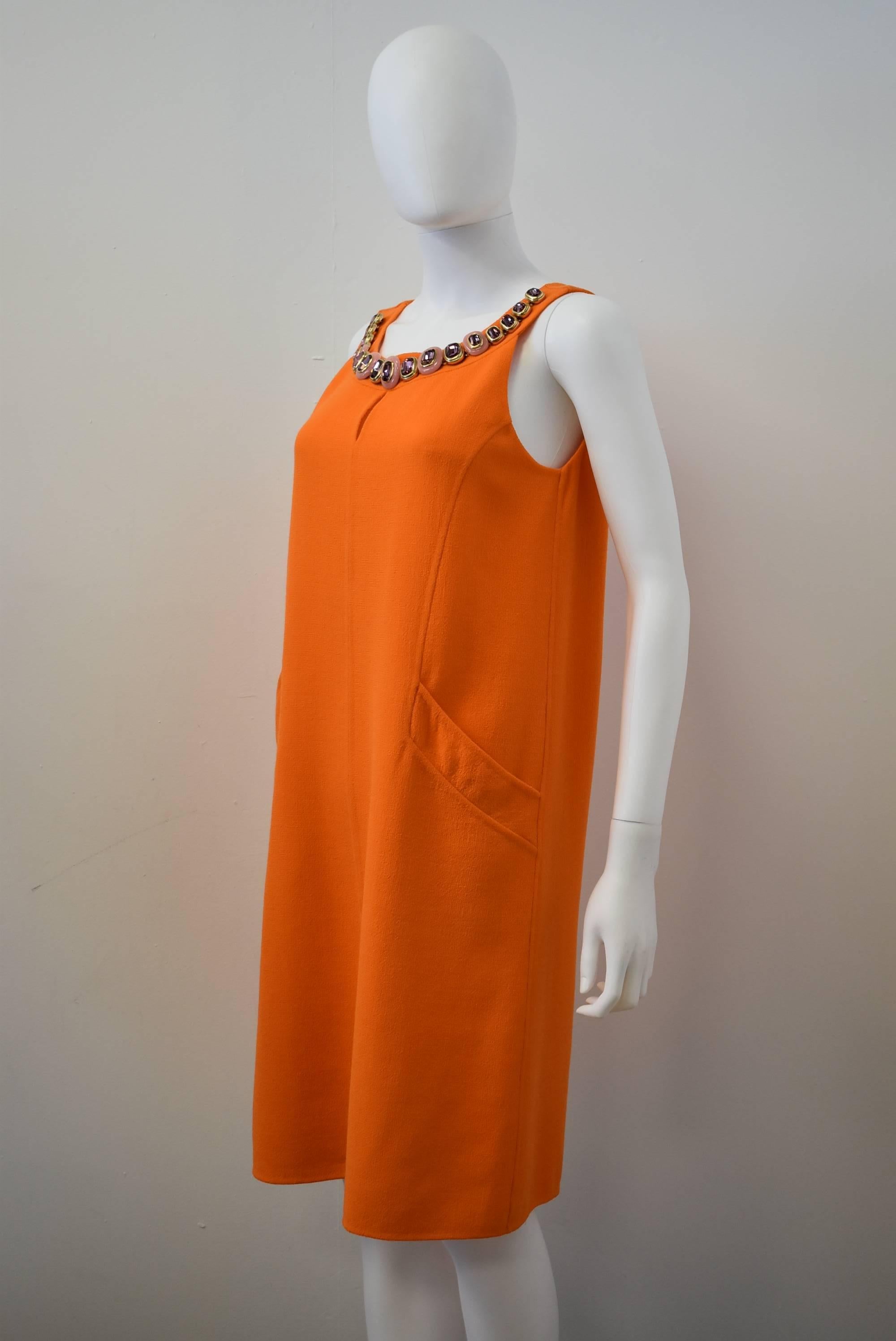 A simple and elegant bright orange shift dress with embellishment along the collar from Oscar de la Renta. The dress has a beautifully simple shape with eye-catching details such as large pockets at the hip, a keyhole cut-out at the décolletage and