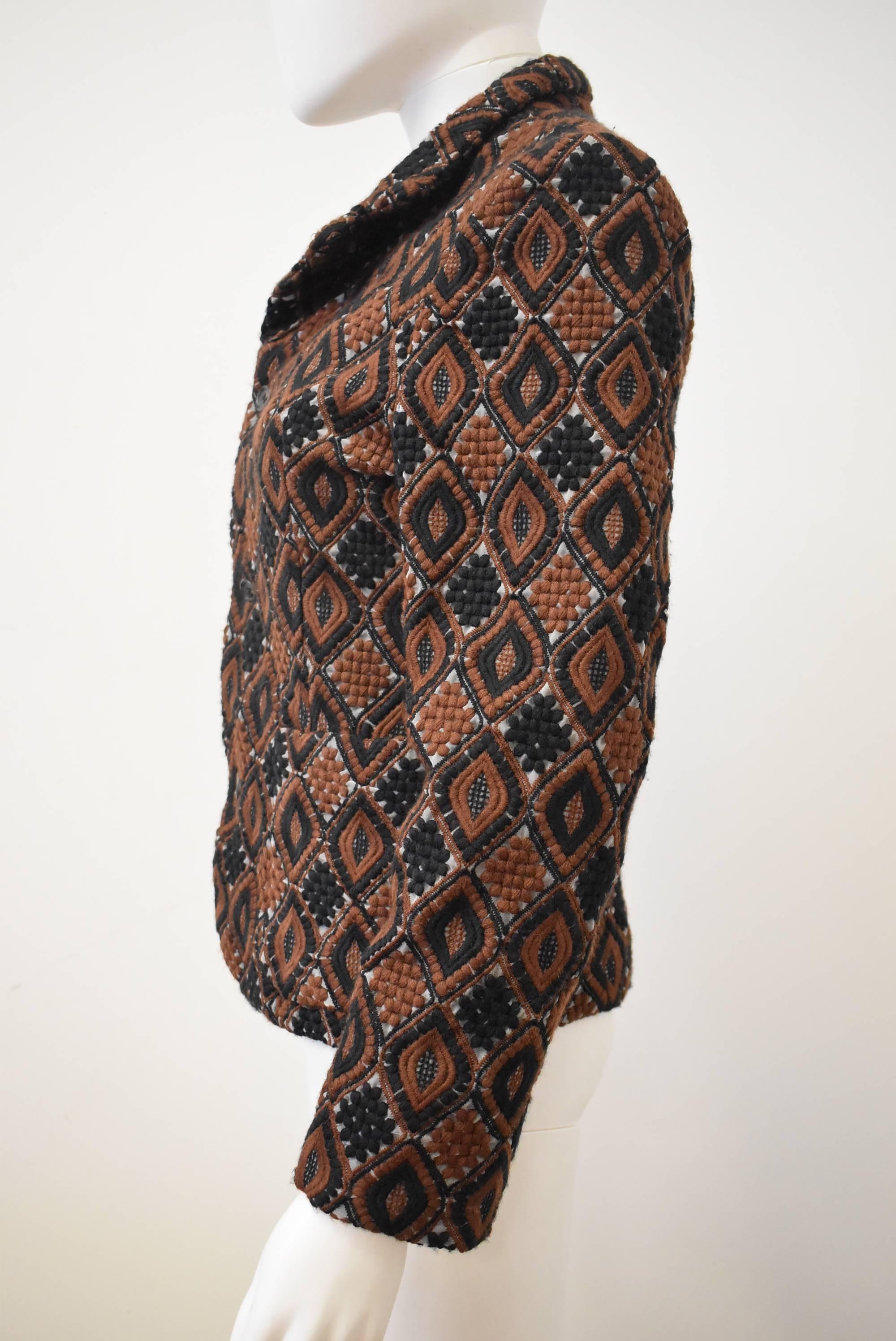 This intricate embroidered jacket is from the Comme Des Garçons / Comme Des Garçons line. The jacket is constructed from a brown and black ethnic style organza fabric with geometric diamond shaped embroidery. The jacket is lined in a sheer black