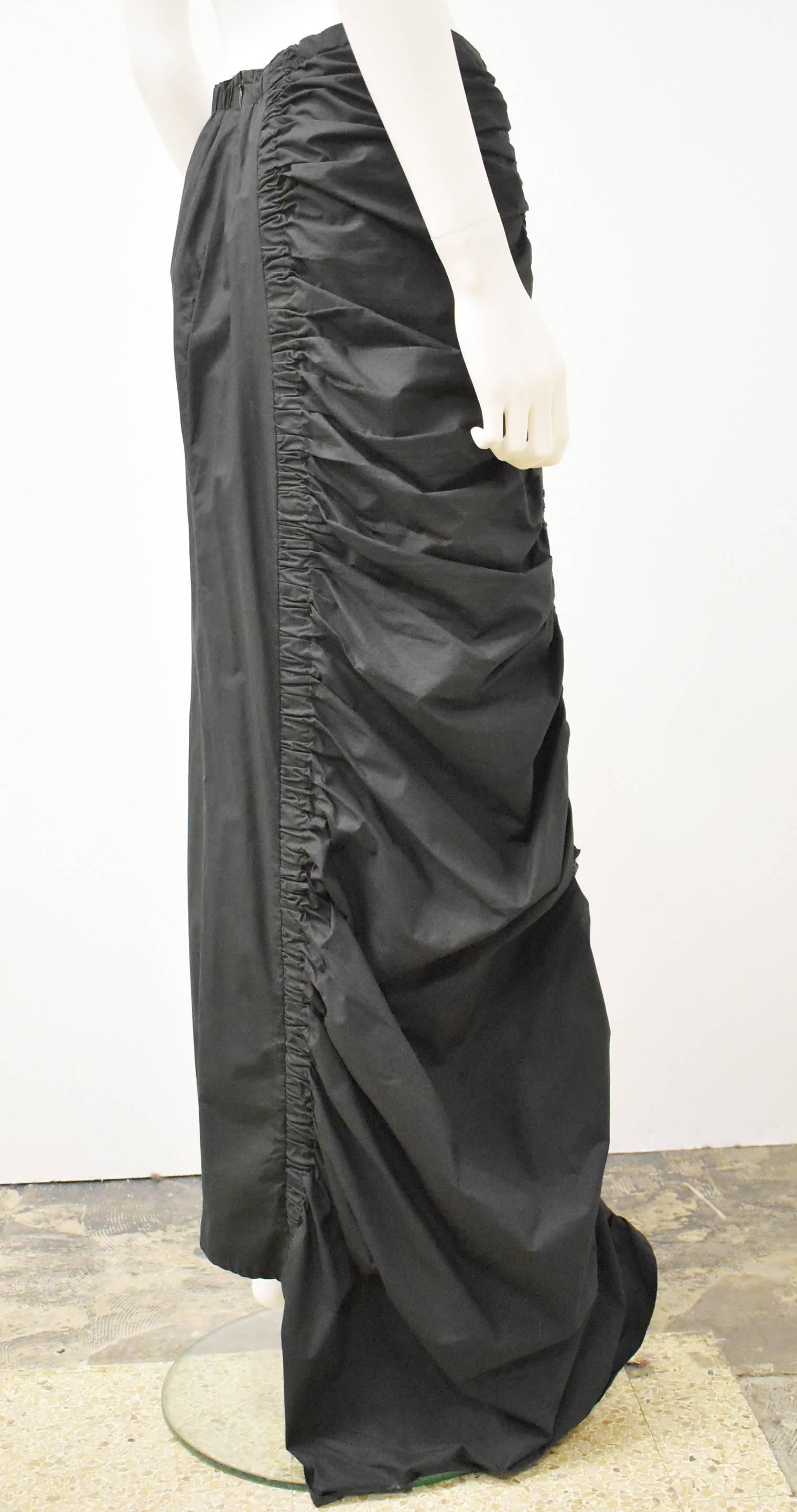 An asymmetric long black skirt from Belgian fashion brand Dries Van Noten. The skirt has an elegant and unusual shape with a simple A-line left side and a contrasting heavily ruched and draped right side and asymmetric hem. The skirt is made from