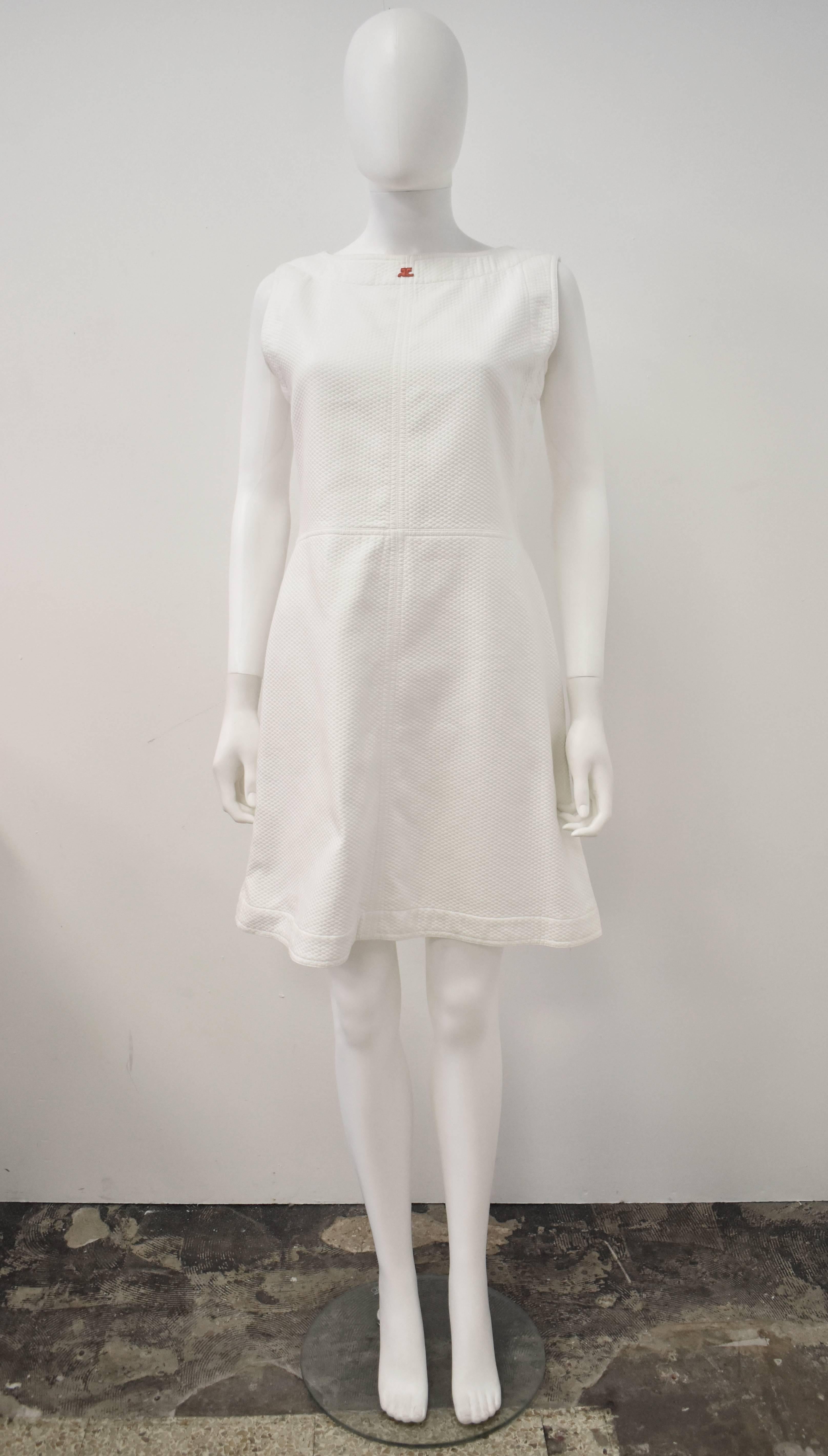 Two piece outfit by French 1960s designer André Courrèges. It features a white textured sleeveless mini dress with red buttons to the back and a cropped jacket with a red zip fastening. The jacket has very light yellowish marks to the sleeves (they