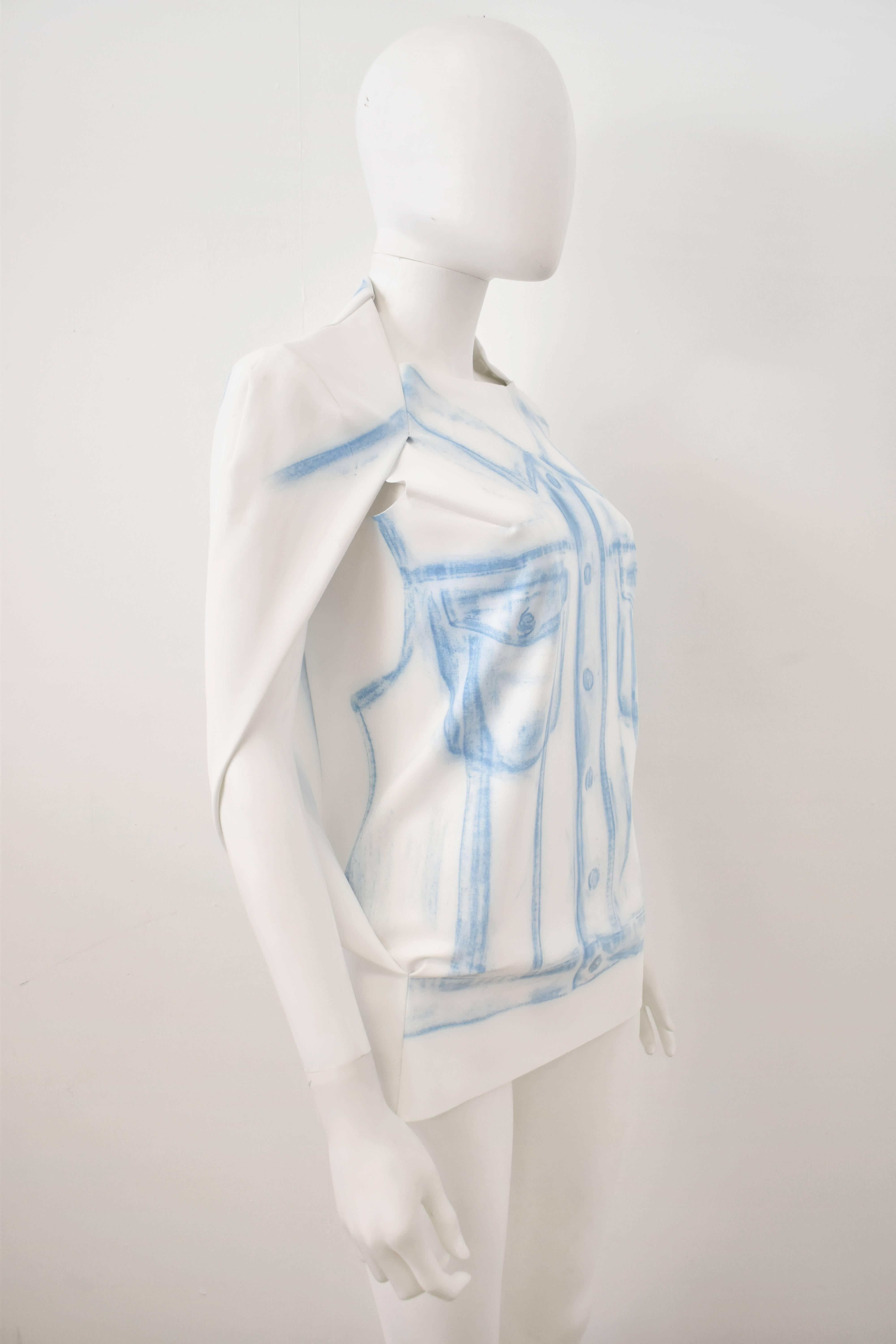 A white cape top from the mainline ‘01’ collection of Maison Martin Margiela. The top has a vest body with an attached capelet that covers the shoulders and back with the arms emerging from the sides. The top is made of a white polyamide and