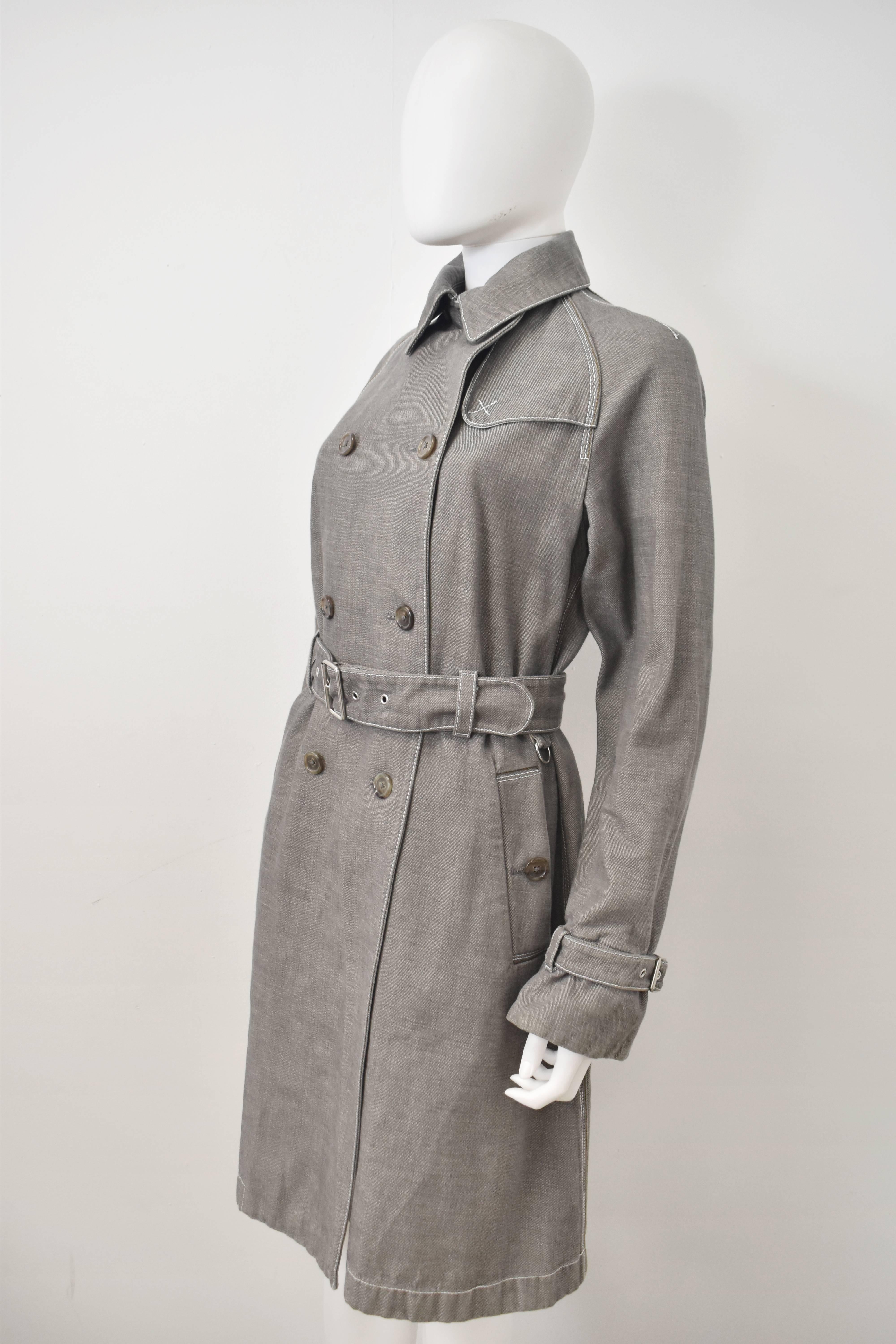 Jil Sander’s twist on the classic trench sees the coat made of grey cotton denim with brown and white contrast stitching along the seams. The coat has a classic trench shape with large collar, double breasted button fastening, waist belt and panel