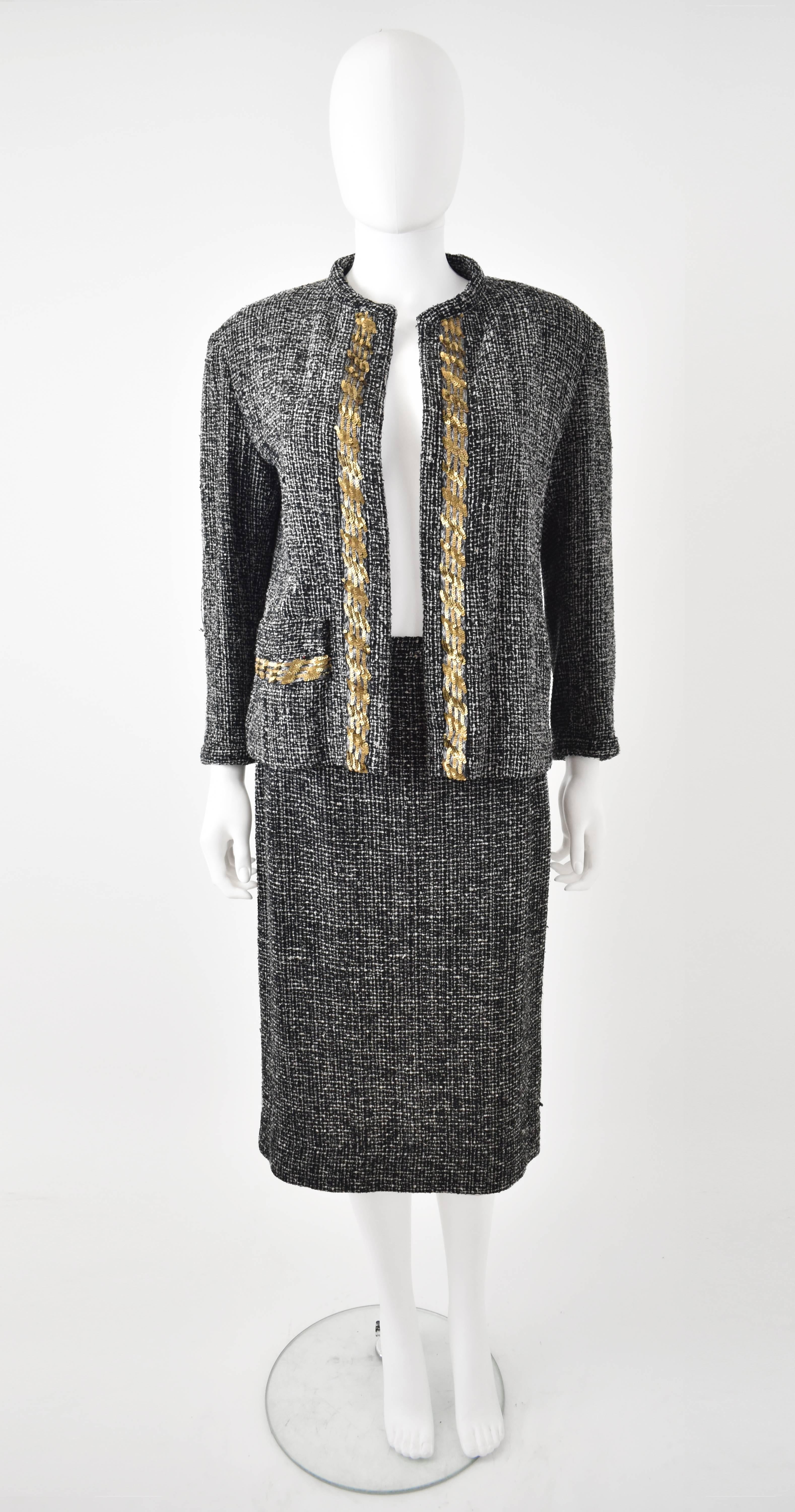 A black and white tweed skirt suit by Yohji Yamamoto. The suit plays on the iconic Chanel skirt suit and adds a Japanese twist with a boxy, open jacket and gold sequin embellishment along the lapels. The skirt has a simple, pencil shape reaching