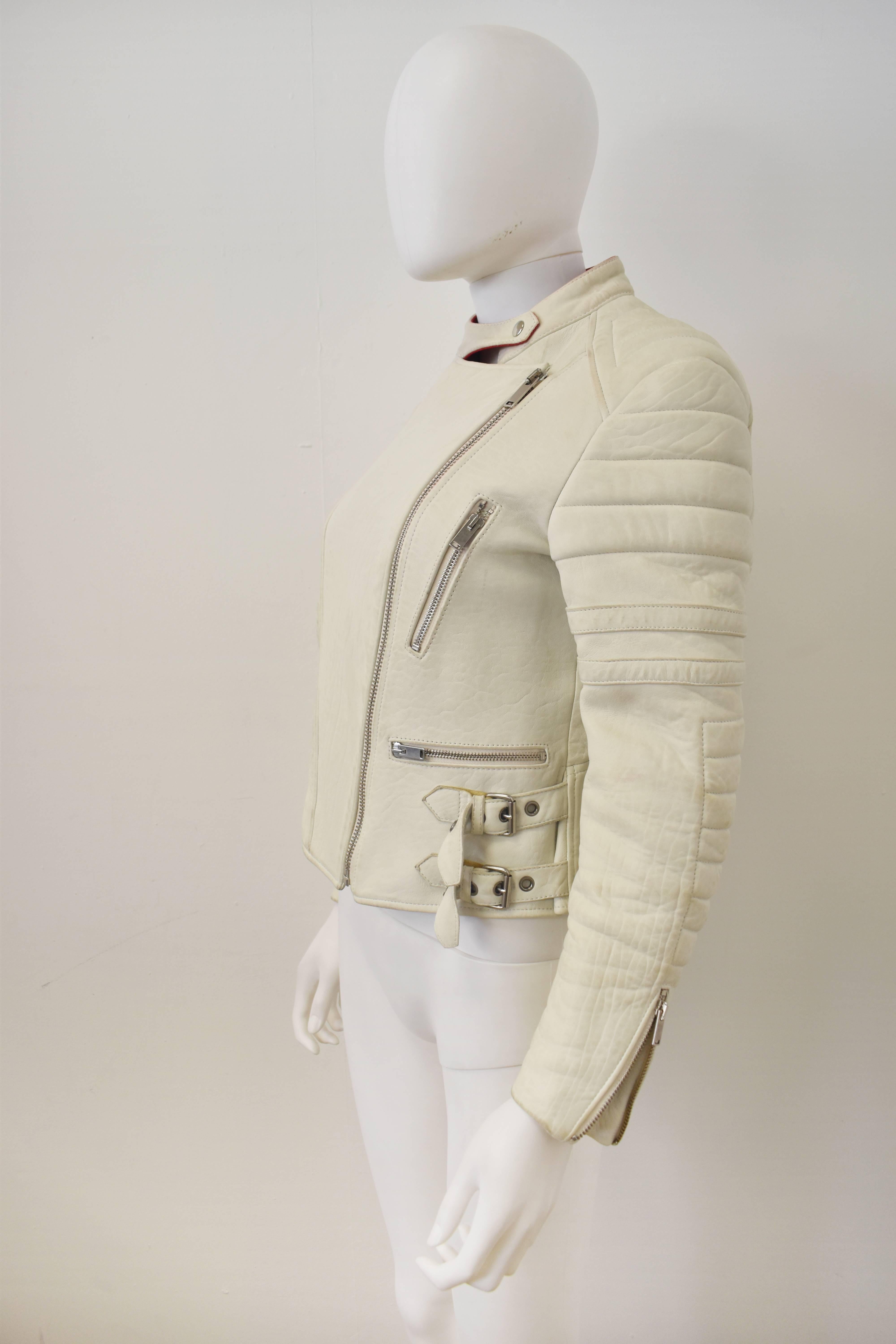 A luxurious cream leather biker jacket from Celine. The jacket bears all the hallmarks of a classic biker jacket with cropped shape, diagonal zip fastening, zip pockets, padded elbows and metal buckle details at the waist. The jacket is made from