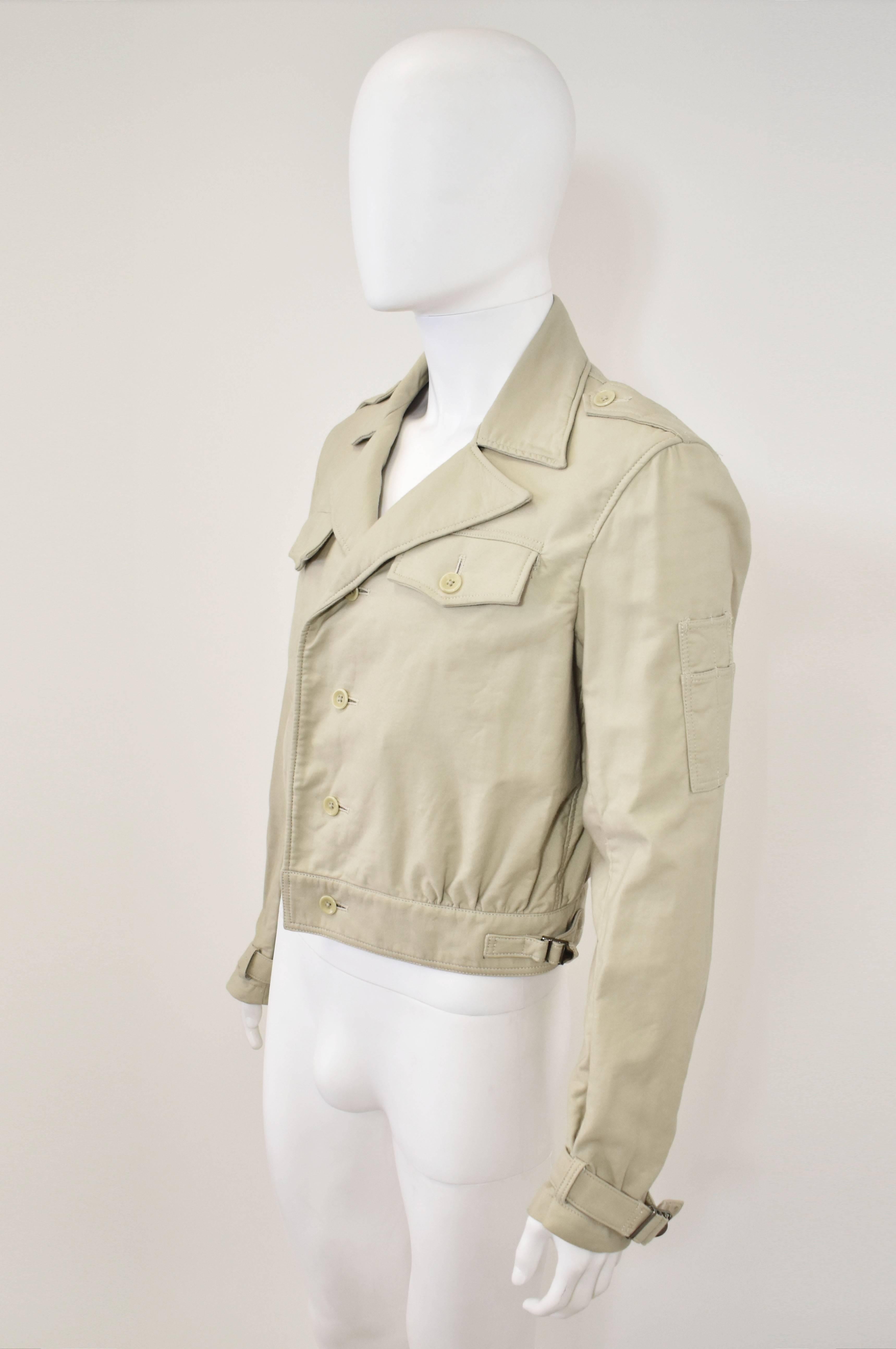 A rare 1980’s Y’s by Yohji Yamamoto beige jacket. It is a cross between a blouson and safari style jacket with a button-down front, cropped body, waistband with buckle details and collar. It has epaulettes on the shoulders and buckles on the