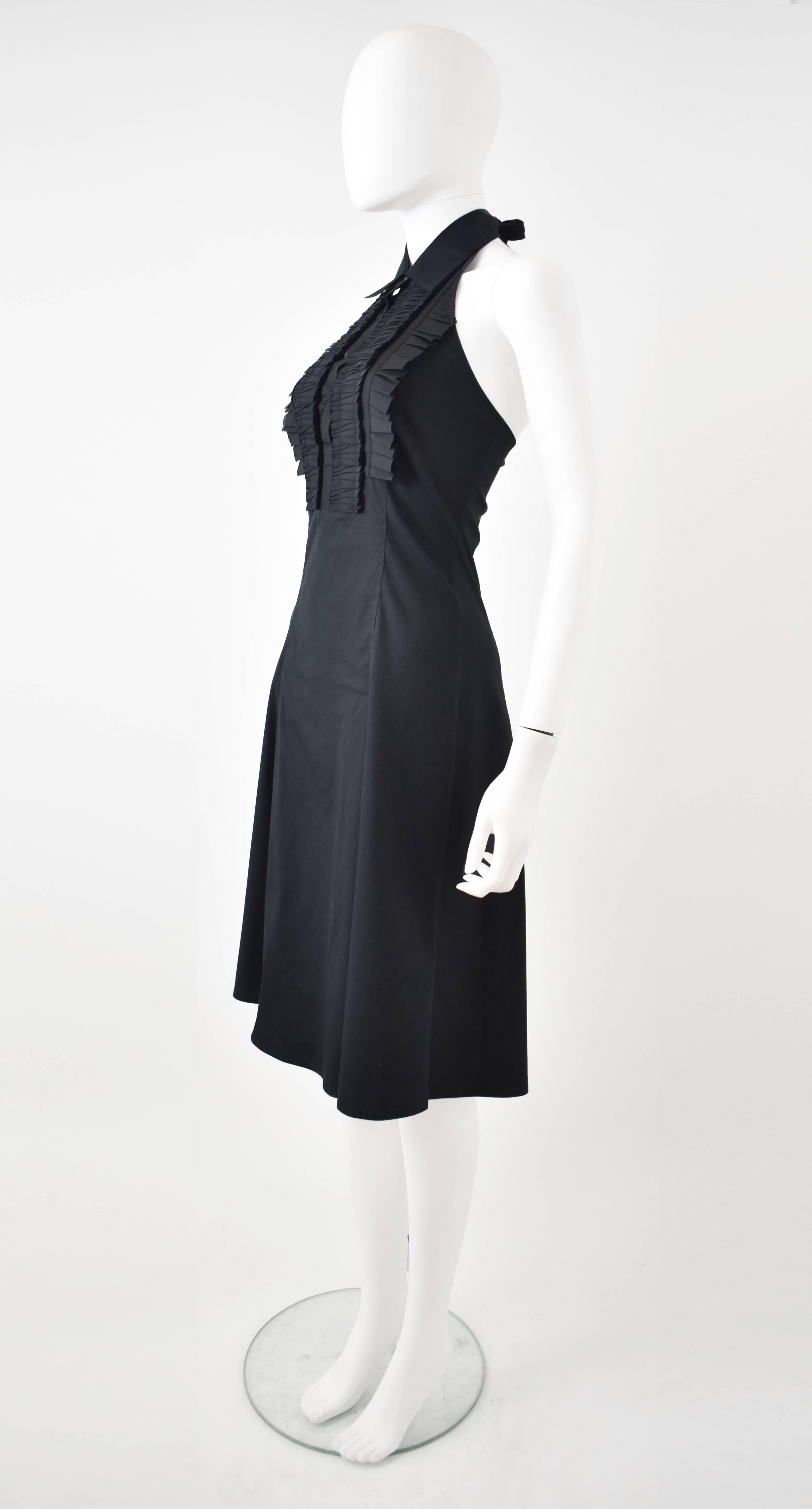 A beautiful and elegant black Summer dress from Celine. The dress has a halterneck design with a tie-fastening at the neck, a slim, fitted shape and a skirt that softly extends with a two pin tucks at the hip to create shape and volume. The front of