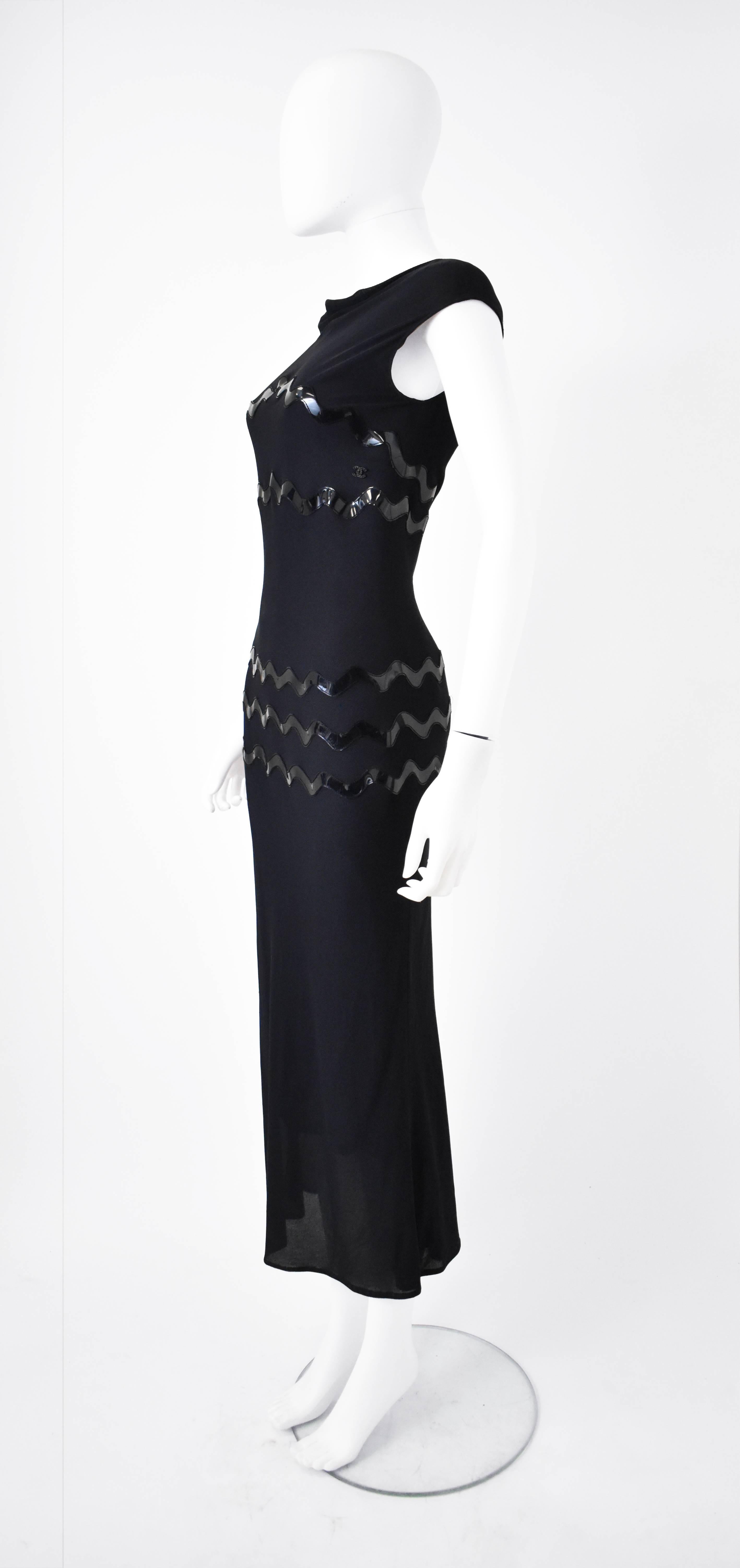 A 1990’s sporty/classic evening dress from Chanel. The dress is made from a dark navy mesh over a layer of dark silk creating a luxurious but sporty look that reflects the popular trends of the 90’s. It also features plastic applique squiggles on
