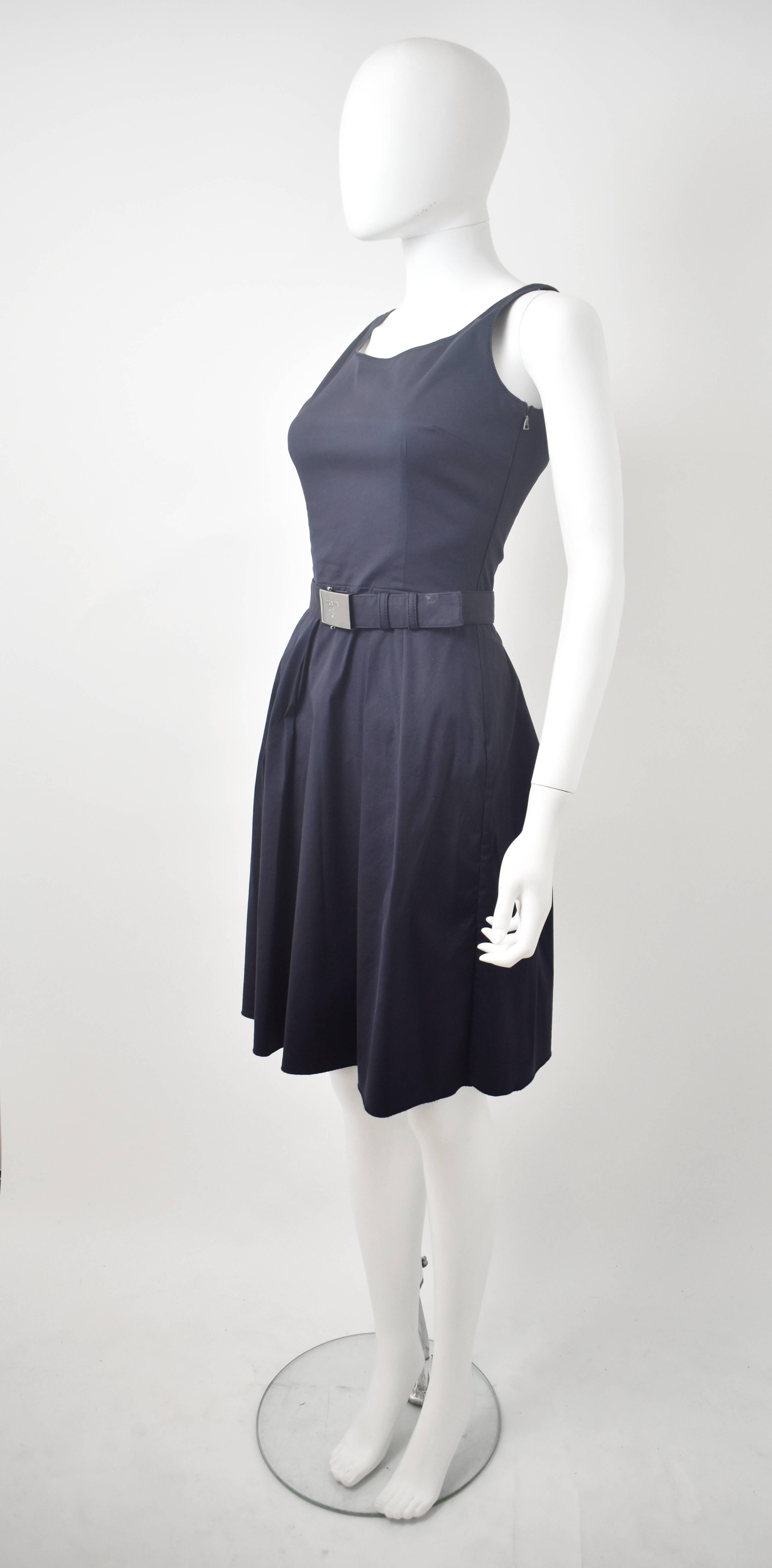 This Prada navy blue dress has a simple, sleeveless design with a fitted bodice and waist and a pleated skirt. The dress is made from a cotton and polyester blend that creates a simultaneously elegant and sportswear-inspired aesthetic synonymous