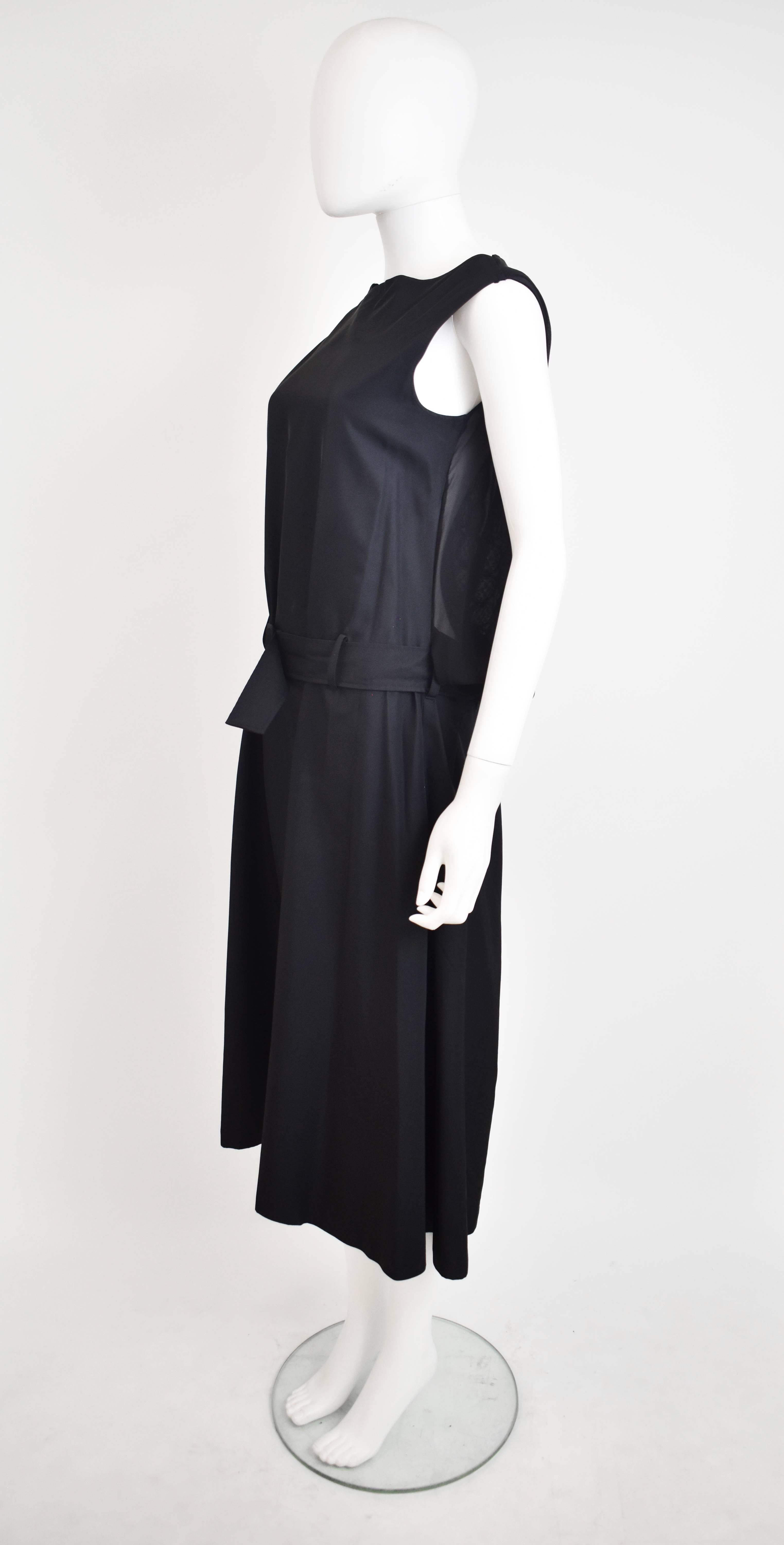 A stunning and rare black dress from Yohji Yamamoto. The dress has a simple shape with vest shoulders, a straight shape and long length. It has a lace panel on the back which peeks out from behind the main structure of the dress. It also has a belt