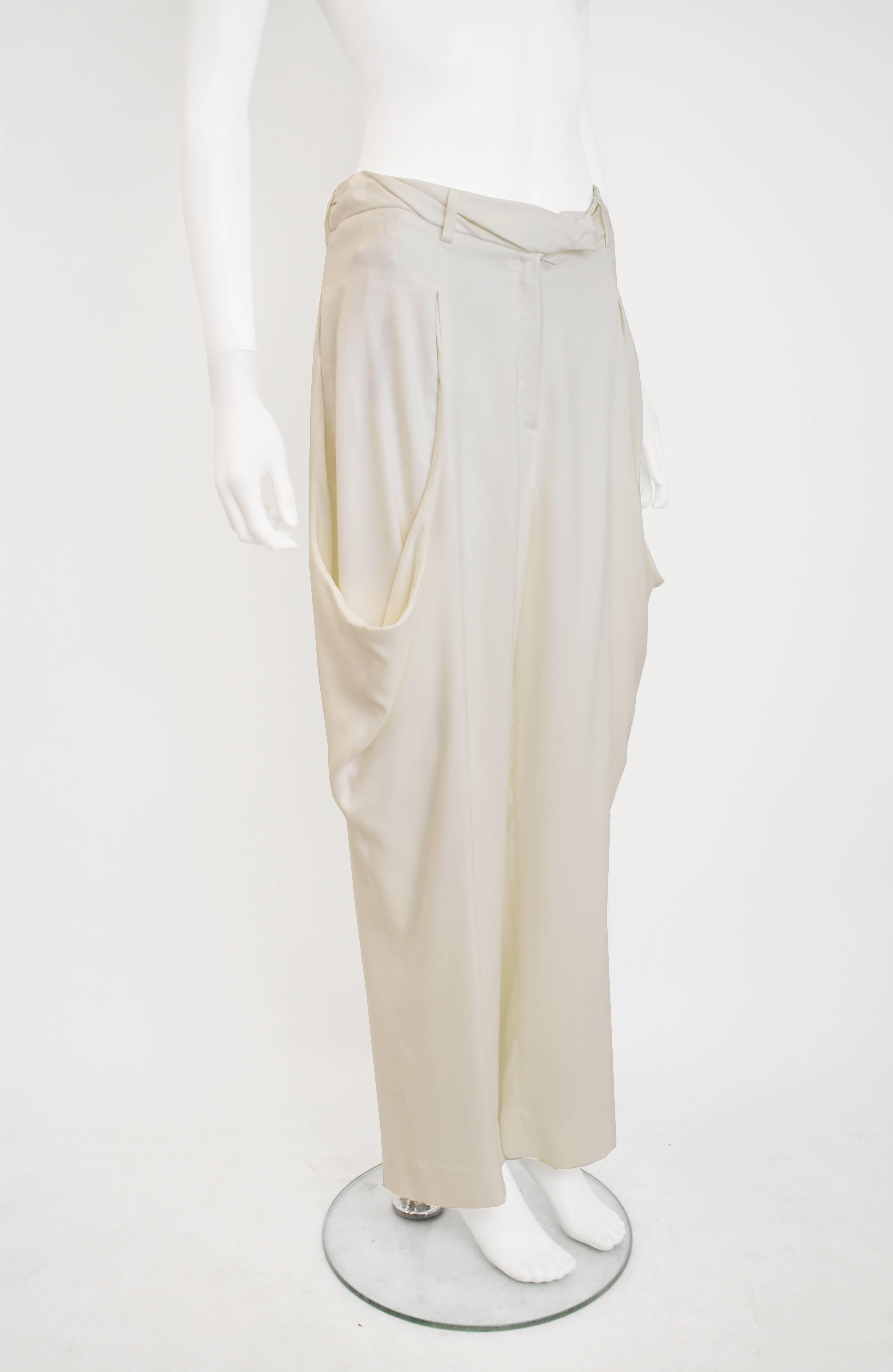 A pair of elegant white cropped trousers by Maison Martin Margiela. The trousers have an interesting shape with a quite wide, cropped cut and oversize pockets on the side that create an extended silhouette. The trousers also have the iconic white