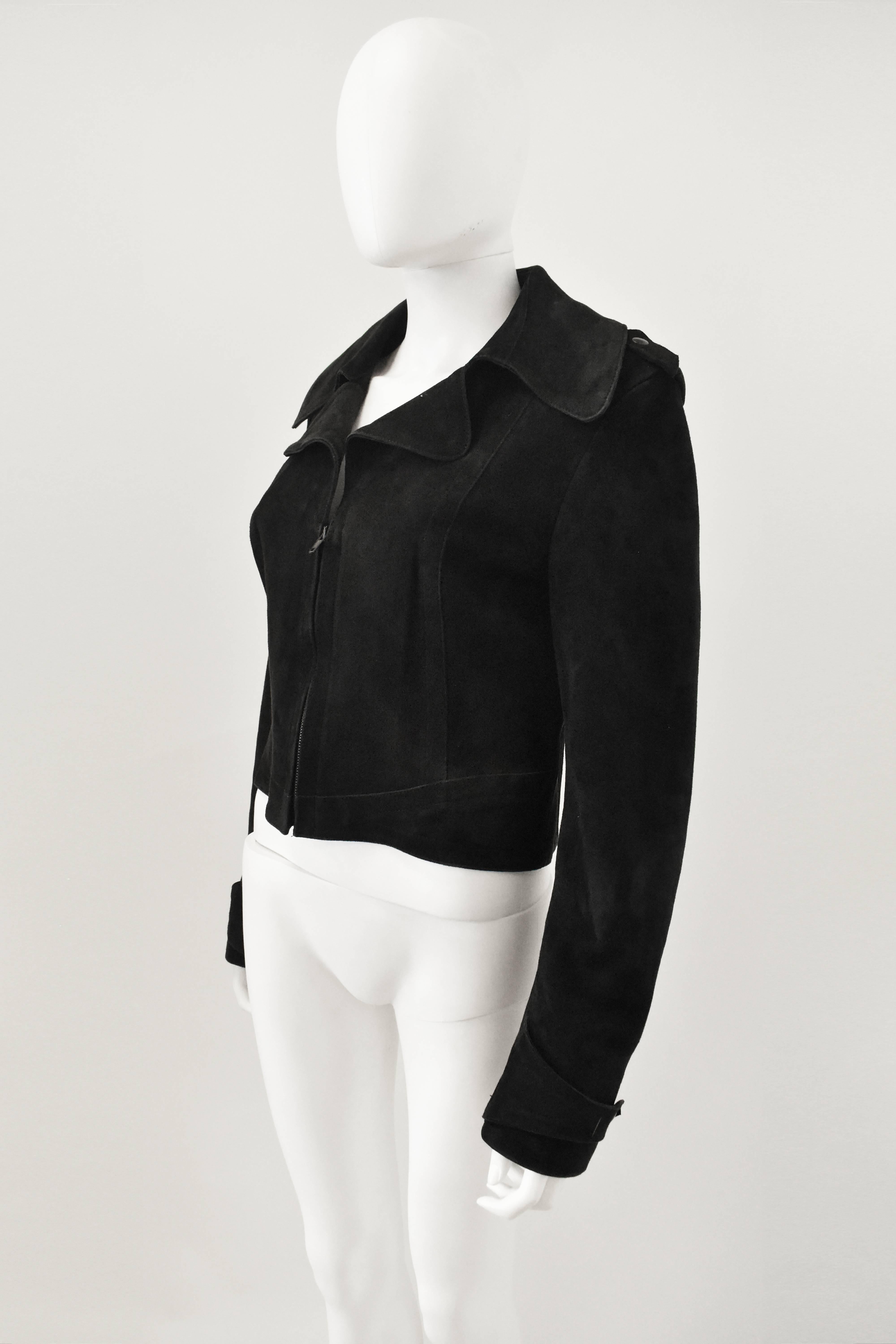A black suede cropped biker jacket from Maison Martin Margiela’s REPLICA line. The jacket is based on a Parisian Biker Jacket from 1968. It has a cropped, boxy shape with a central zip, large collar and stitching around the waist. It also features