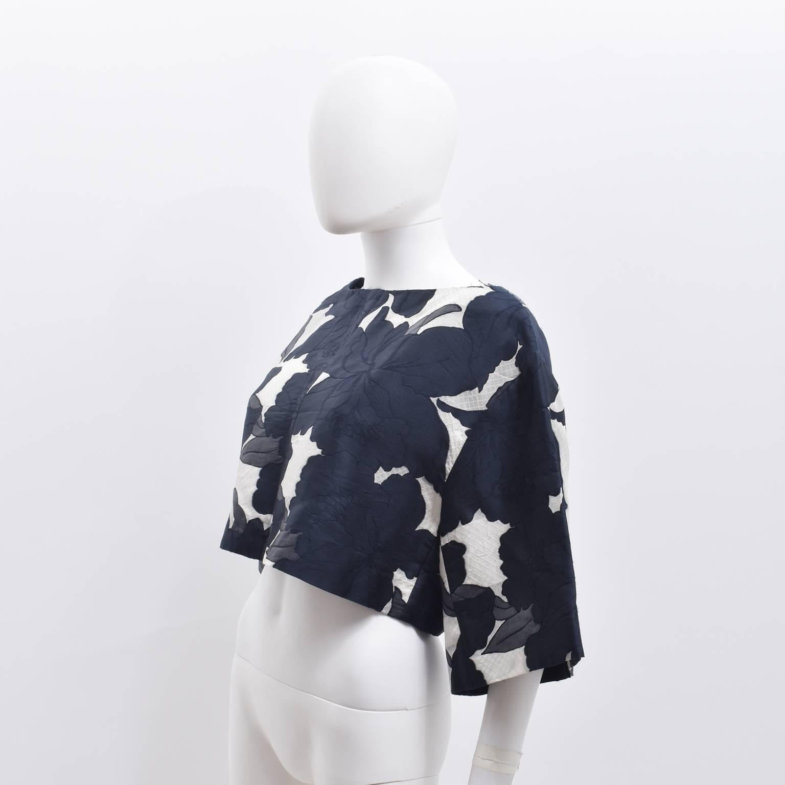 An elegant and contemporary floral cropped top from French label Chloe. The top has a boxy, cropped shape with wide, three-quarter length sleeves and a wide neckline. It is made from a silk and polyester blend jacquard material with a large floral
