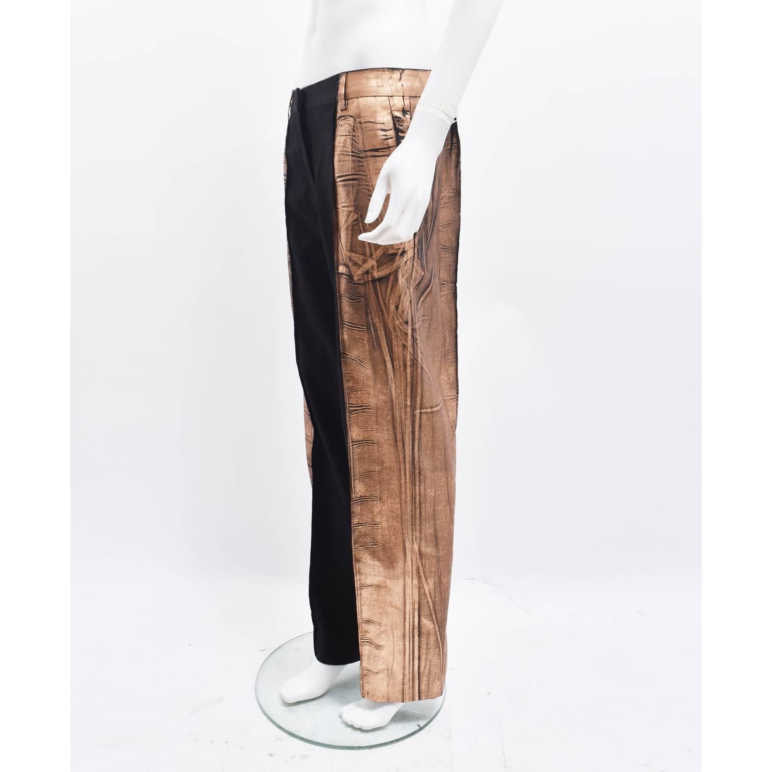 
A pair of Martin Margiela black trousers with metallic bronze ‘paint’ decorating the sides. The trousers have a simple, straight cut that sit on the waist with a regular fit. The Margiela twist comes from the metallic bronze embellishment that