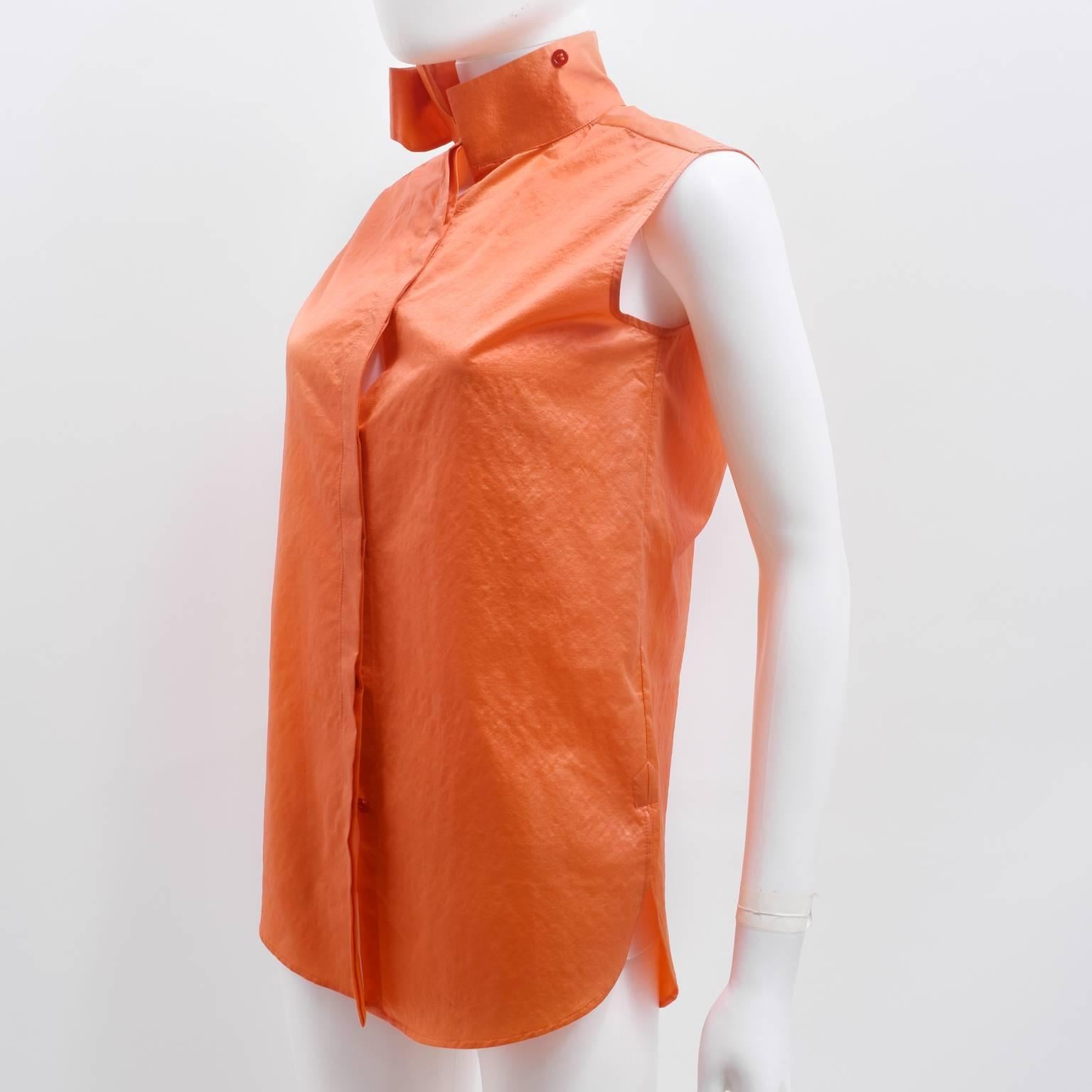 A contemporary sleeveless shirt in a bright orange silk blend material from Balenciaga. The shirt has a straight, slightly oversized cut with a concealed button fastening. It also has an interesting collar that resembles a Mandarin collar but can be