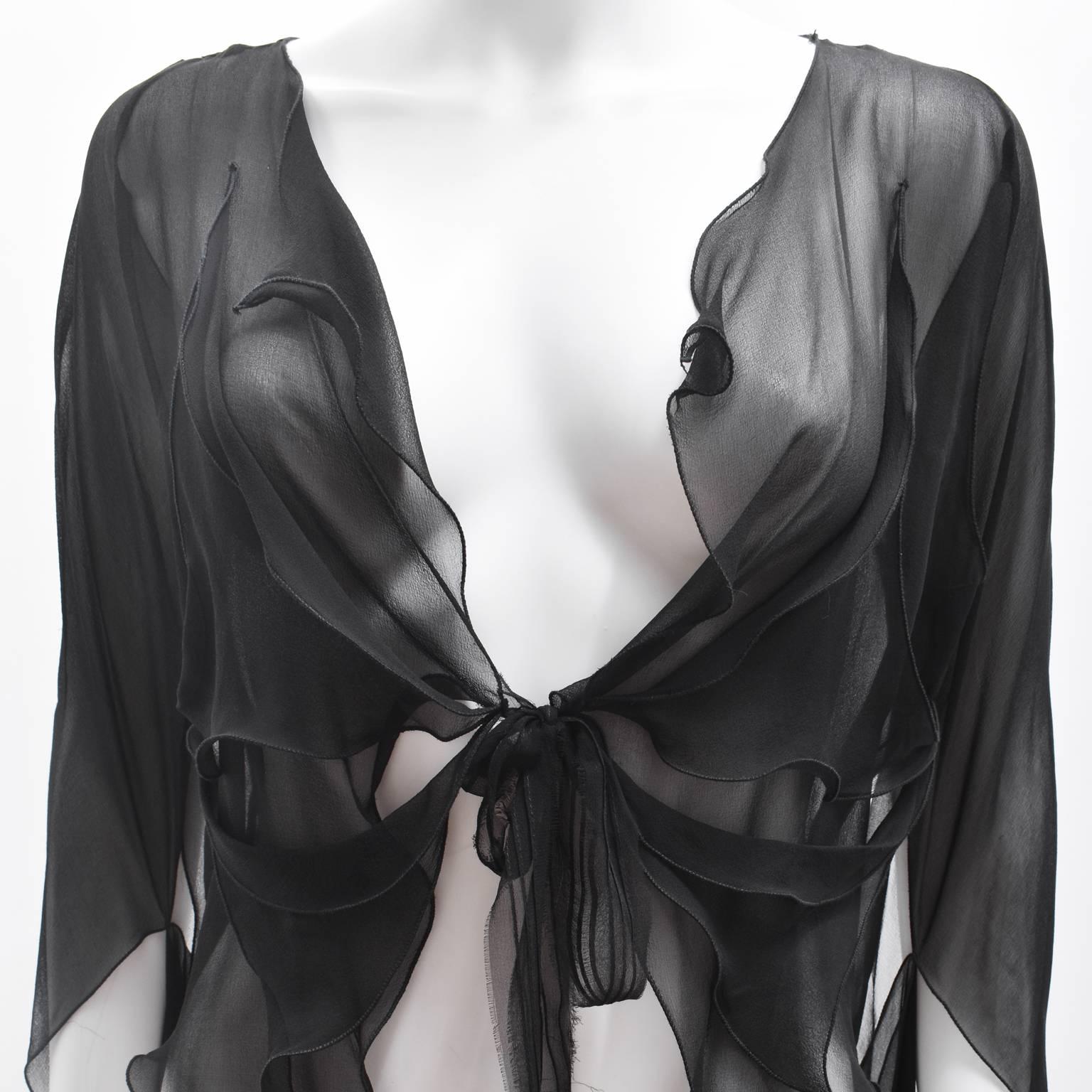 An elegant black sheer silk blouse from British designer Roland Mouret. Dating from around 2010, the blouse has a flowing, water-like drapery with elongated sleeves and a tie-fastening at the front. The blouse has interesting cut-out holes with the