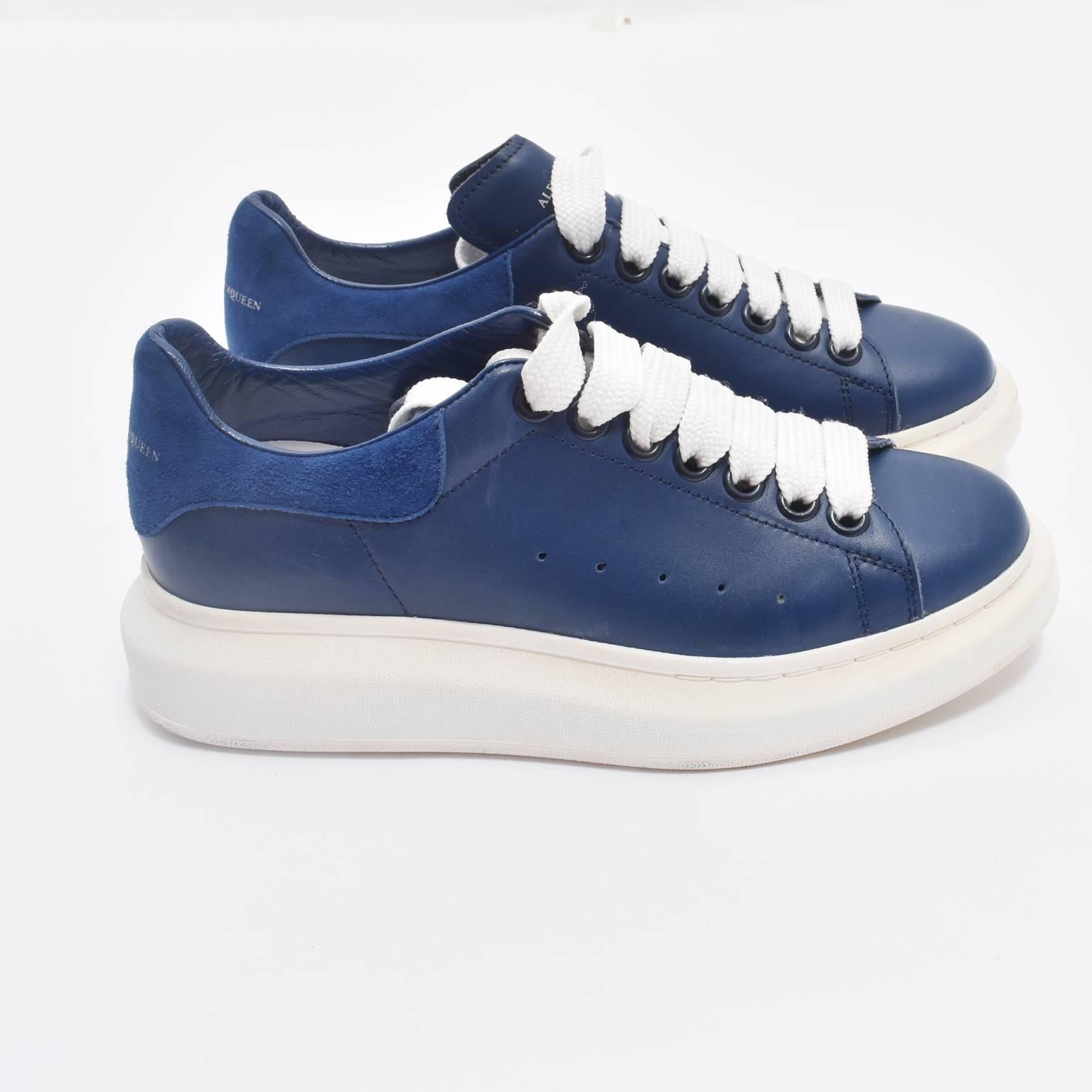 A pair of brand new navy blue sneakers from Alexander McQueen. The sneakers are made from soft leather with a contrasting chunky white rubber sole with a height of 1.5 inches. The sneakers have a lace-up fastening and come with their original dust