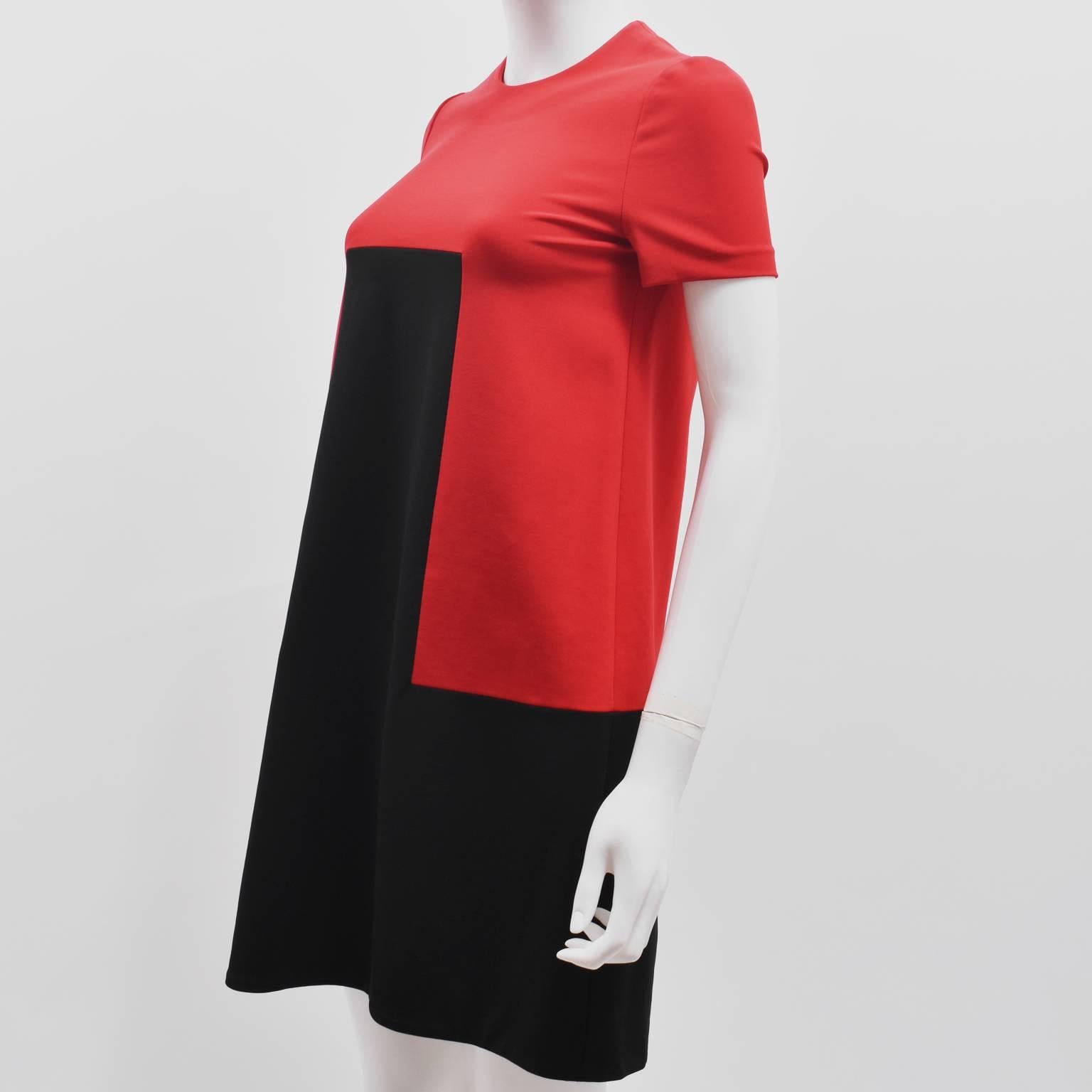 An elegant and simple shift dress from Alexander McQueen. The dress has short sleeves, and a triangular A-line cut. The dress is made from a Rayon blend in contrast red and black in a geometric shape. It is in excellent condition with no signs of