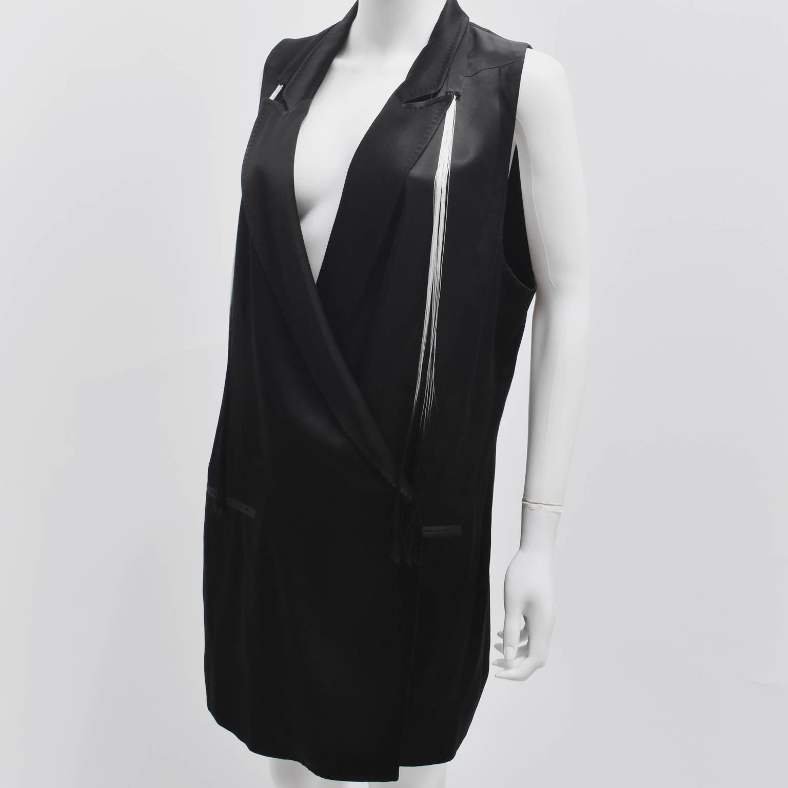 An elegant and interesting tuxedo jacket from Belgian designer Ann Demeulemeester. The jacket has a sleeveless cut with a longline, oversized shape. It has a straight cut with a large notched collar and a crossover button fastening on the left side