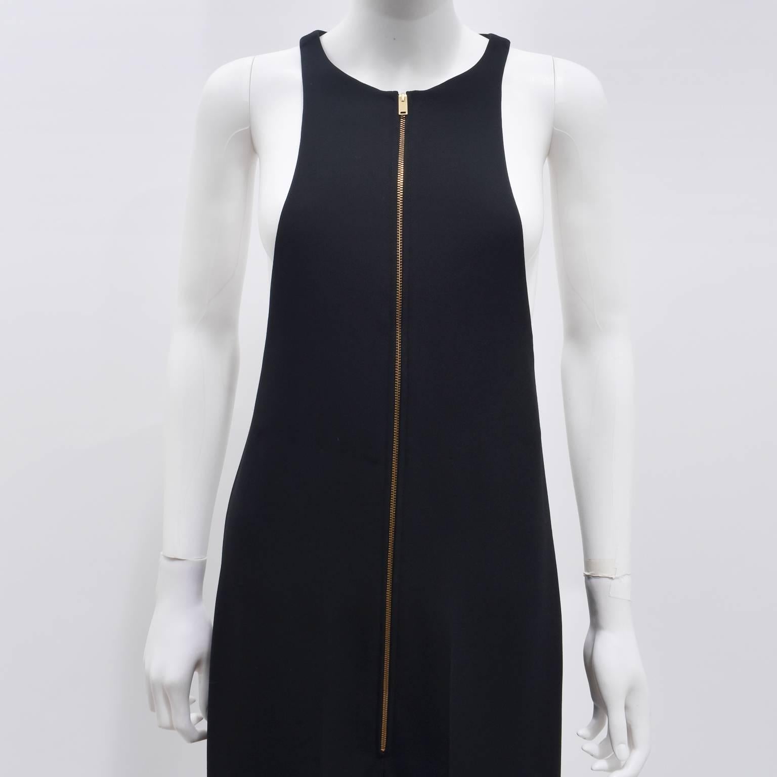 An elegant black sleeveless jumpsuit from Celine. The jumpsuit has a slim tailored fit with long trousers and a pleat down the centre fold. The top part of the jumpsuit is a sleeveless, bib-style top with open sides. There is also a gold zip
