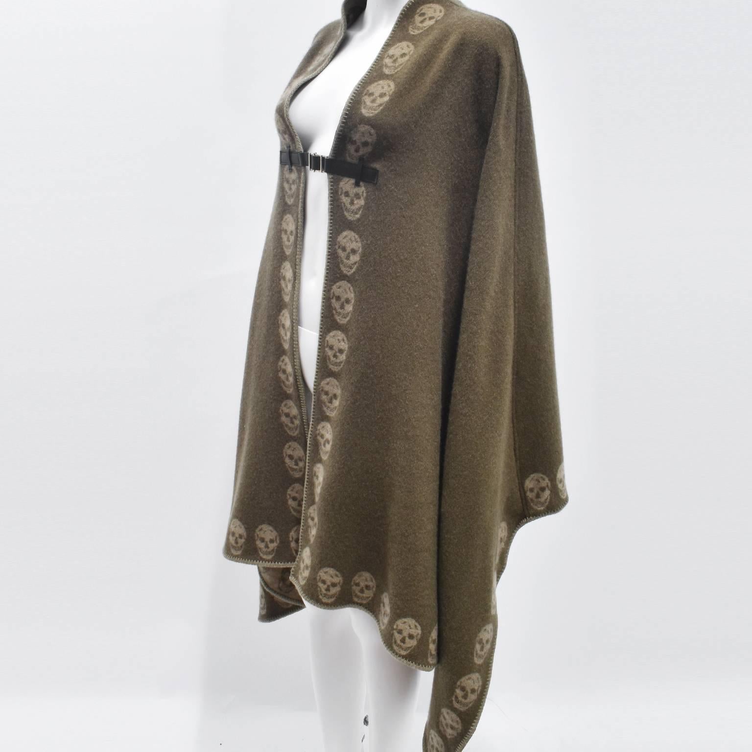 A beautiful and cosy khaki cashmere blanket poncho from Alexander McQueen. The poncho has a simple, one size shape with small curves that echo the shape of the shoulders. The intarsia knit is made from 100% cashmere in a khaki colour with McQueen’s